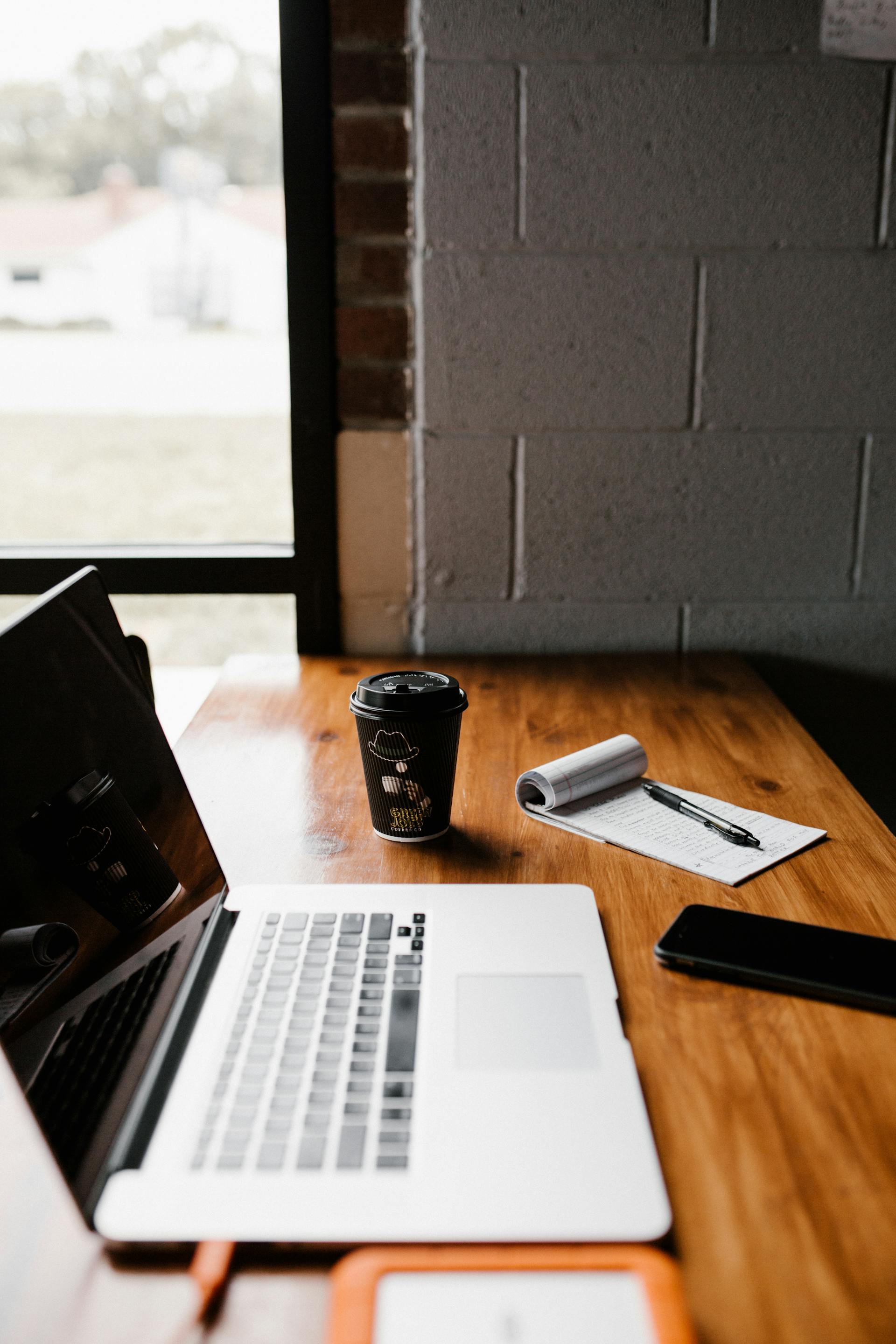 Une tasse de café à emporter à côté d'un ordinateur portable sur un bureau | Source : Pexels