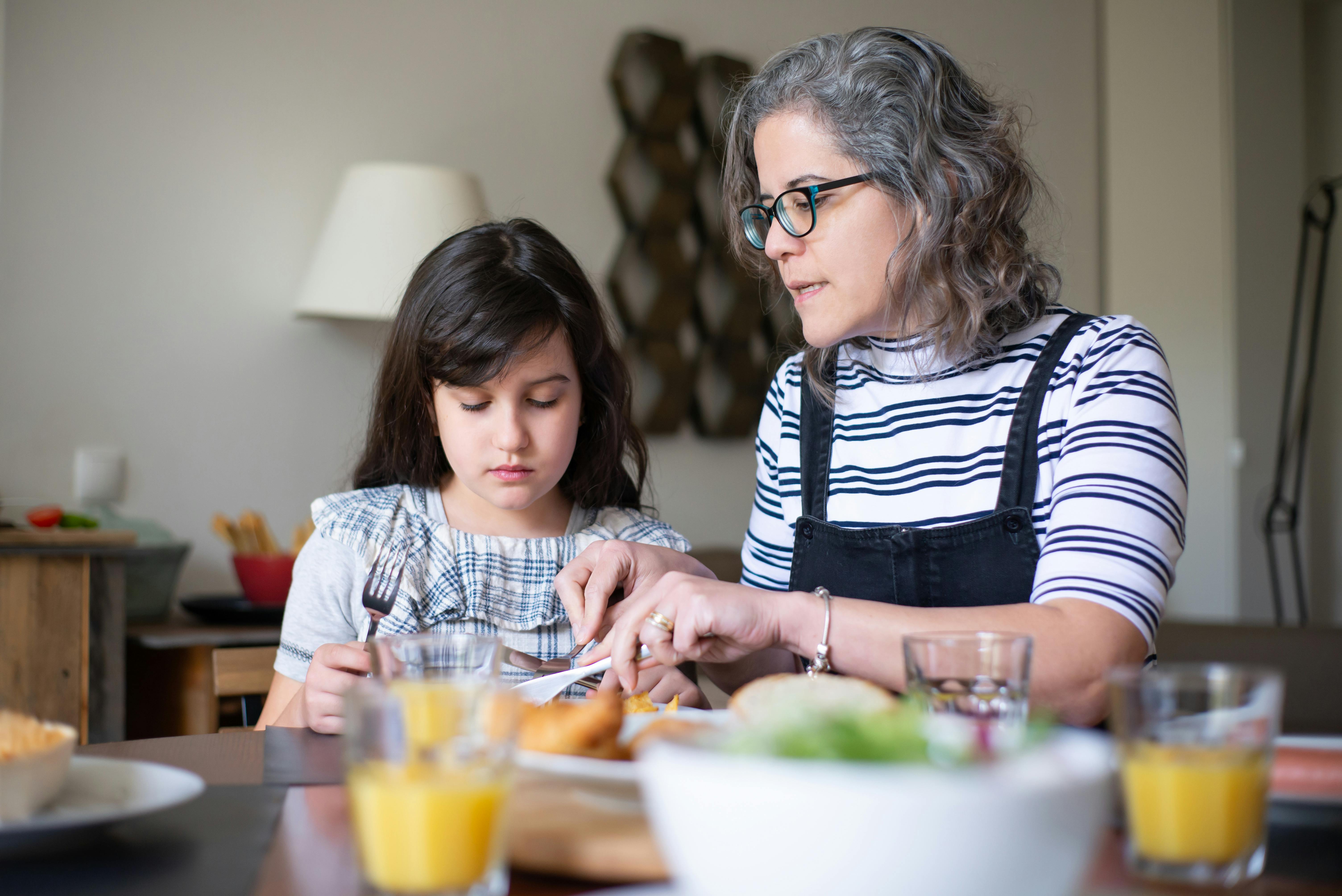 Woman talking to a young girl at a dinner table | Source: Pexels