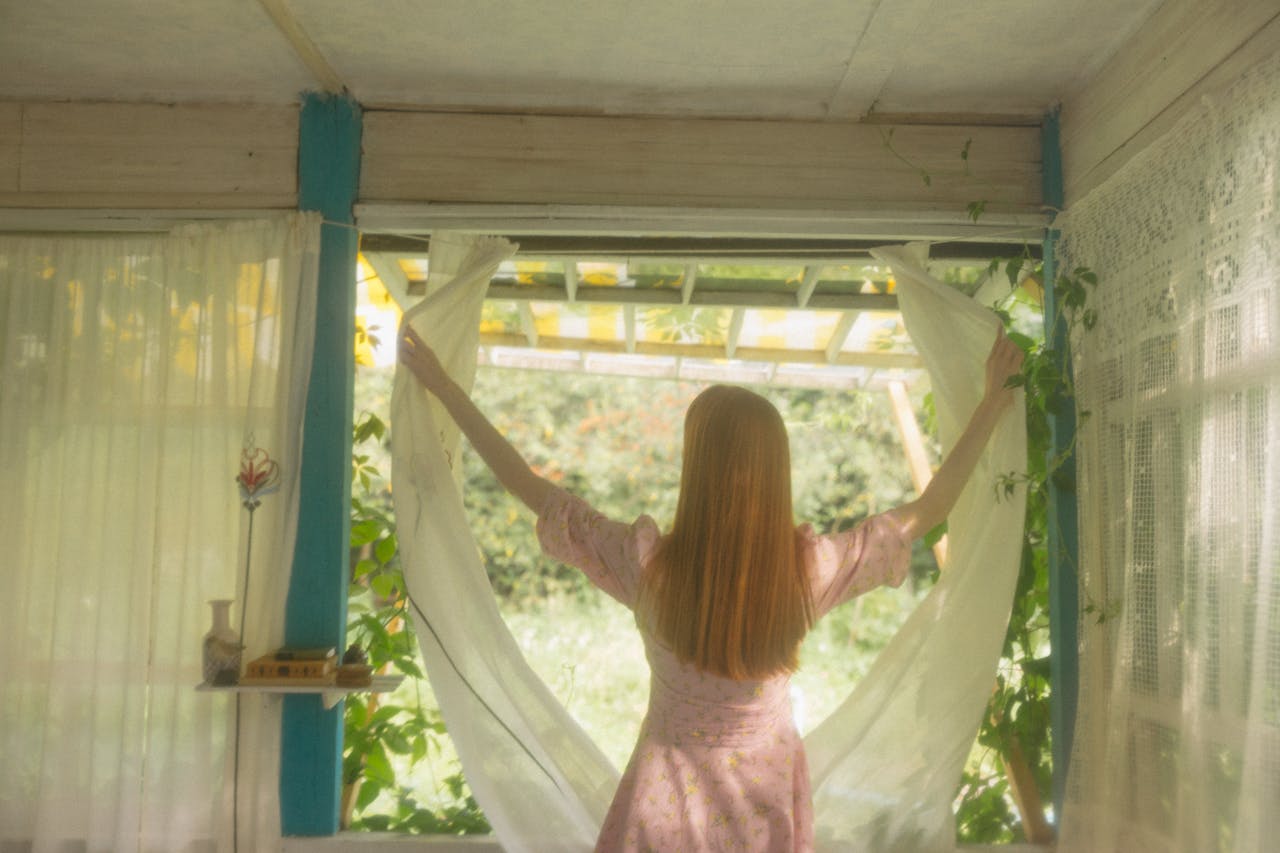 A woman opening a curtain | Source: Pexels