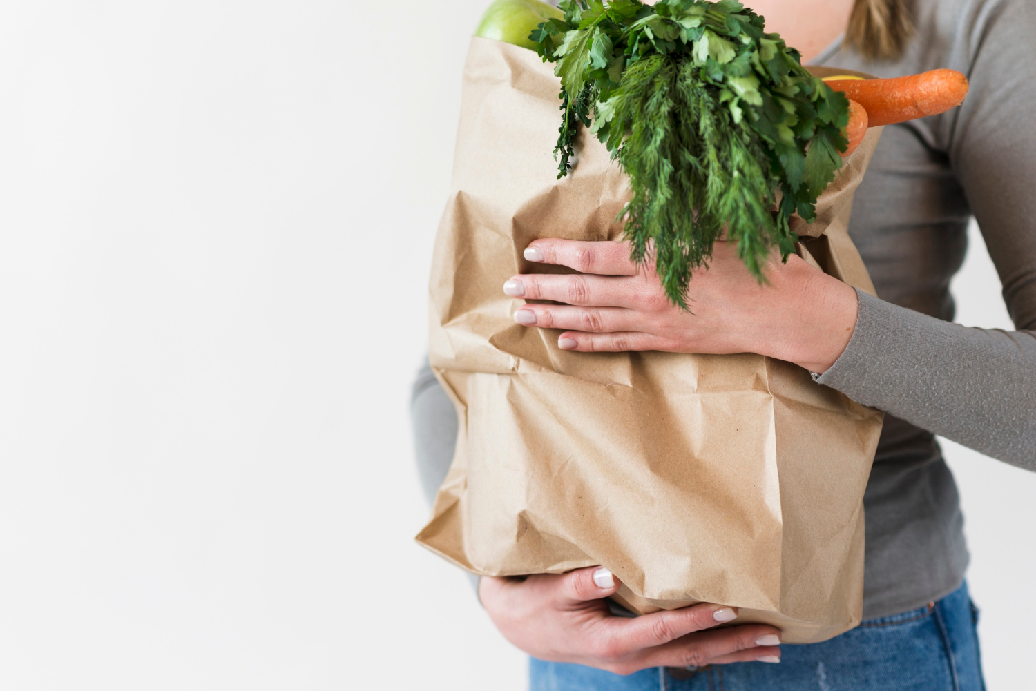 A woman holding a bag of groceries | Source: Freepik