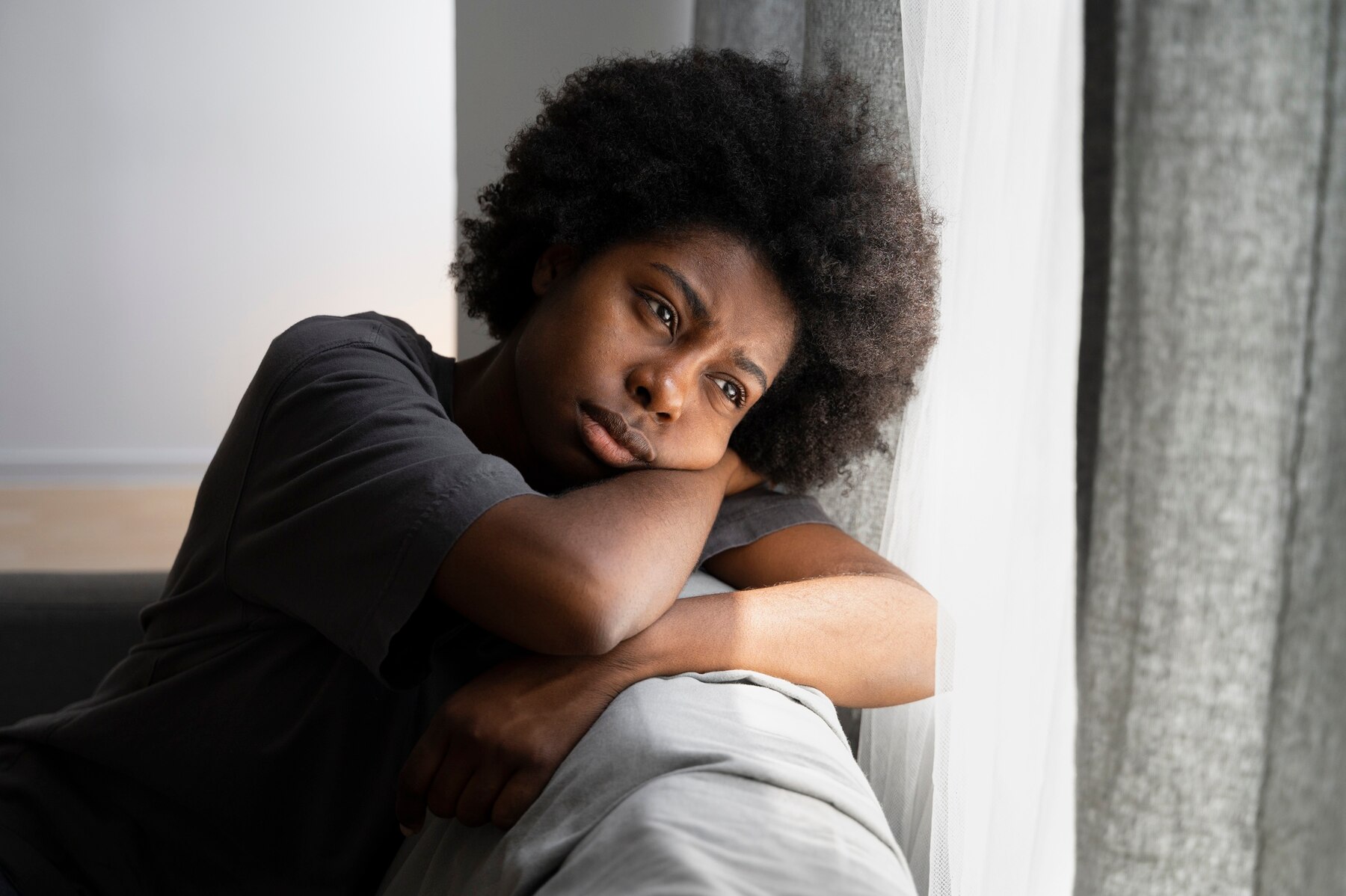 A sad woman laying on her couch | Source: Freepik