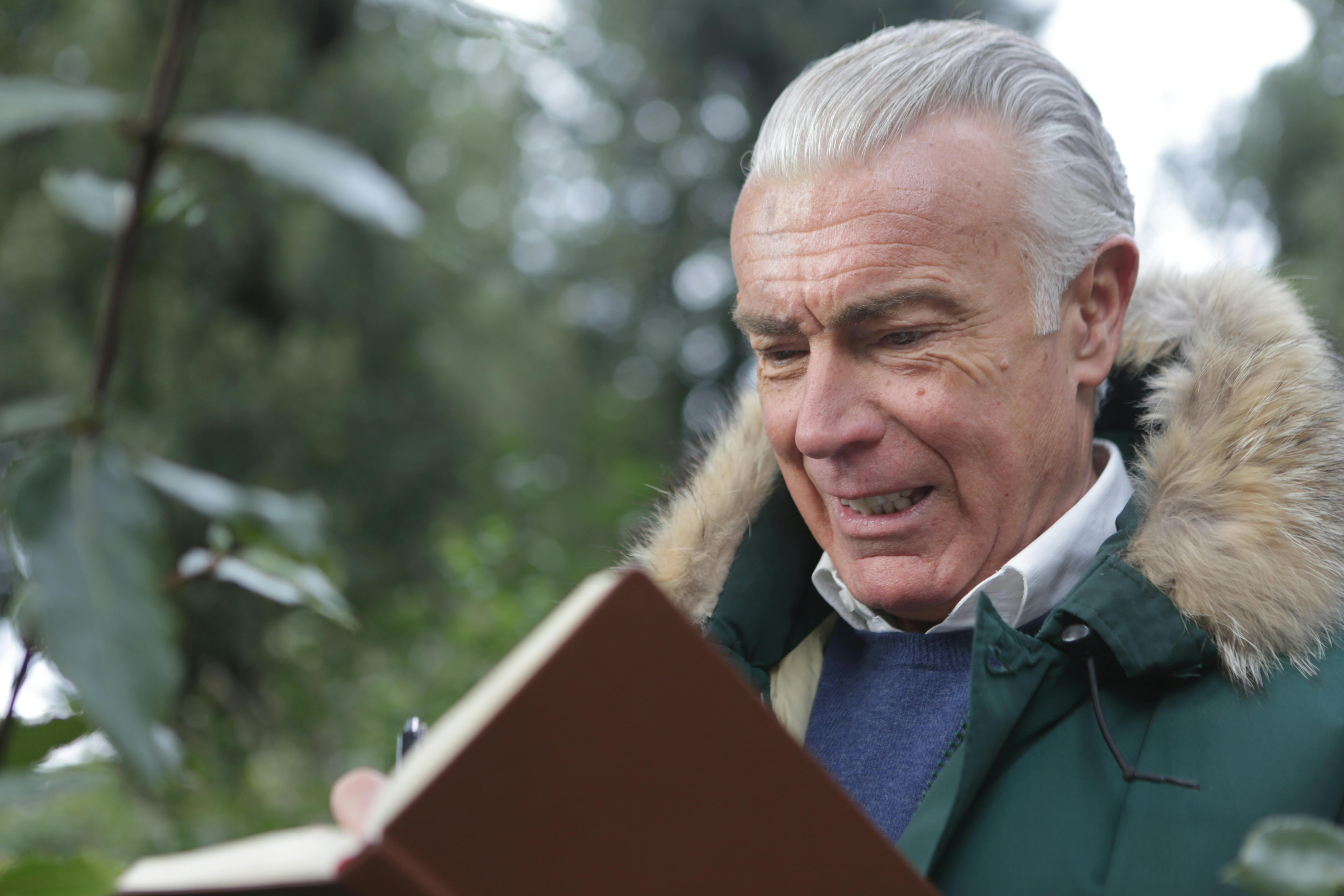 Um homem mais velho com um livro aberto à sua frente | Fonte: Pexels