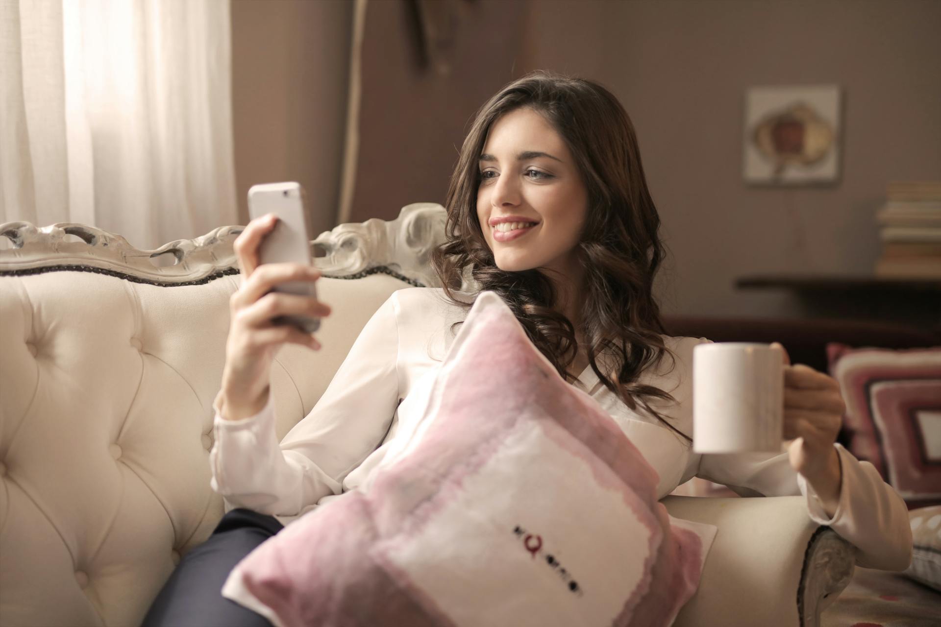 A woman smiling at her phone | Source: Pexels