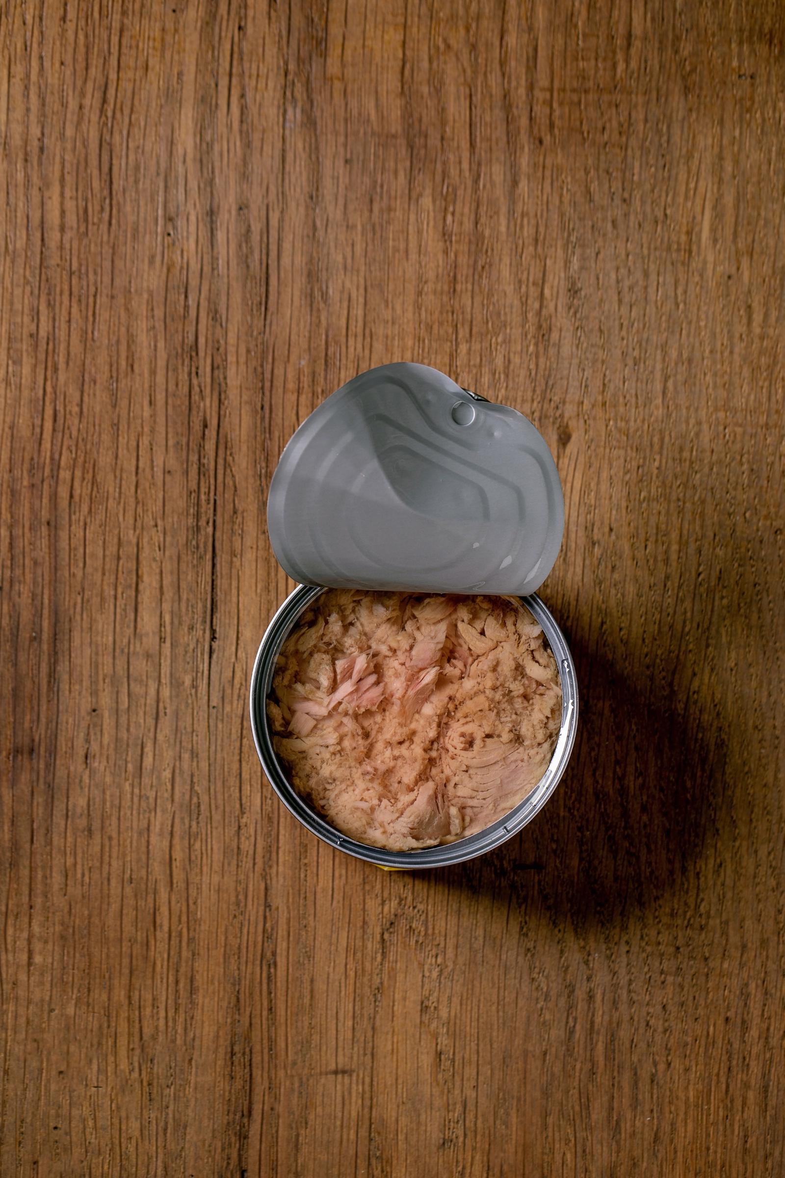 Canned tuna fish in oil in opened can over a wooden background | Source: Getty Images