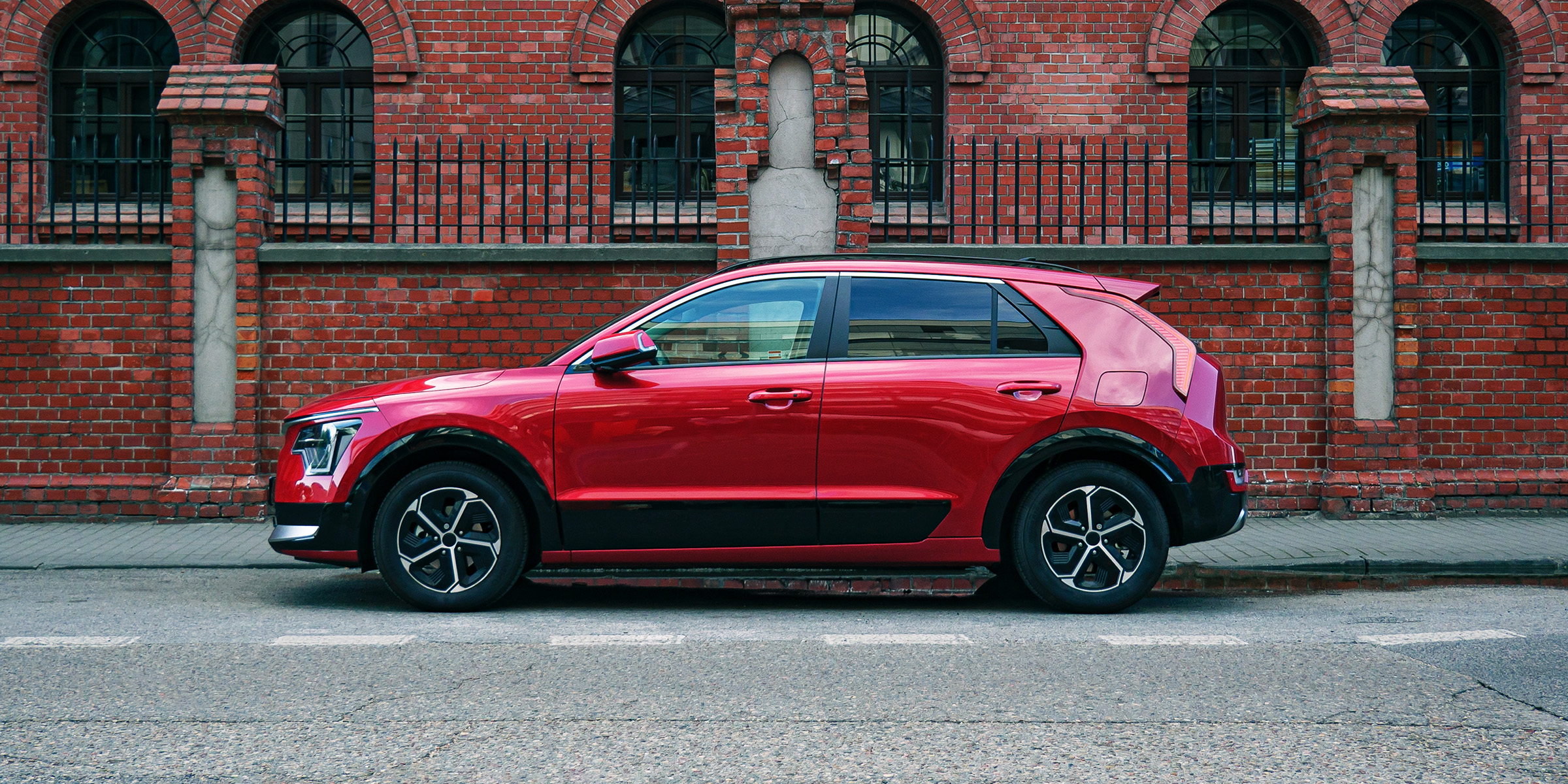 A red SUV parked beside a brick building | Source: Shutterstock