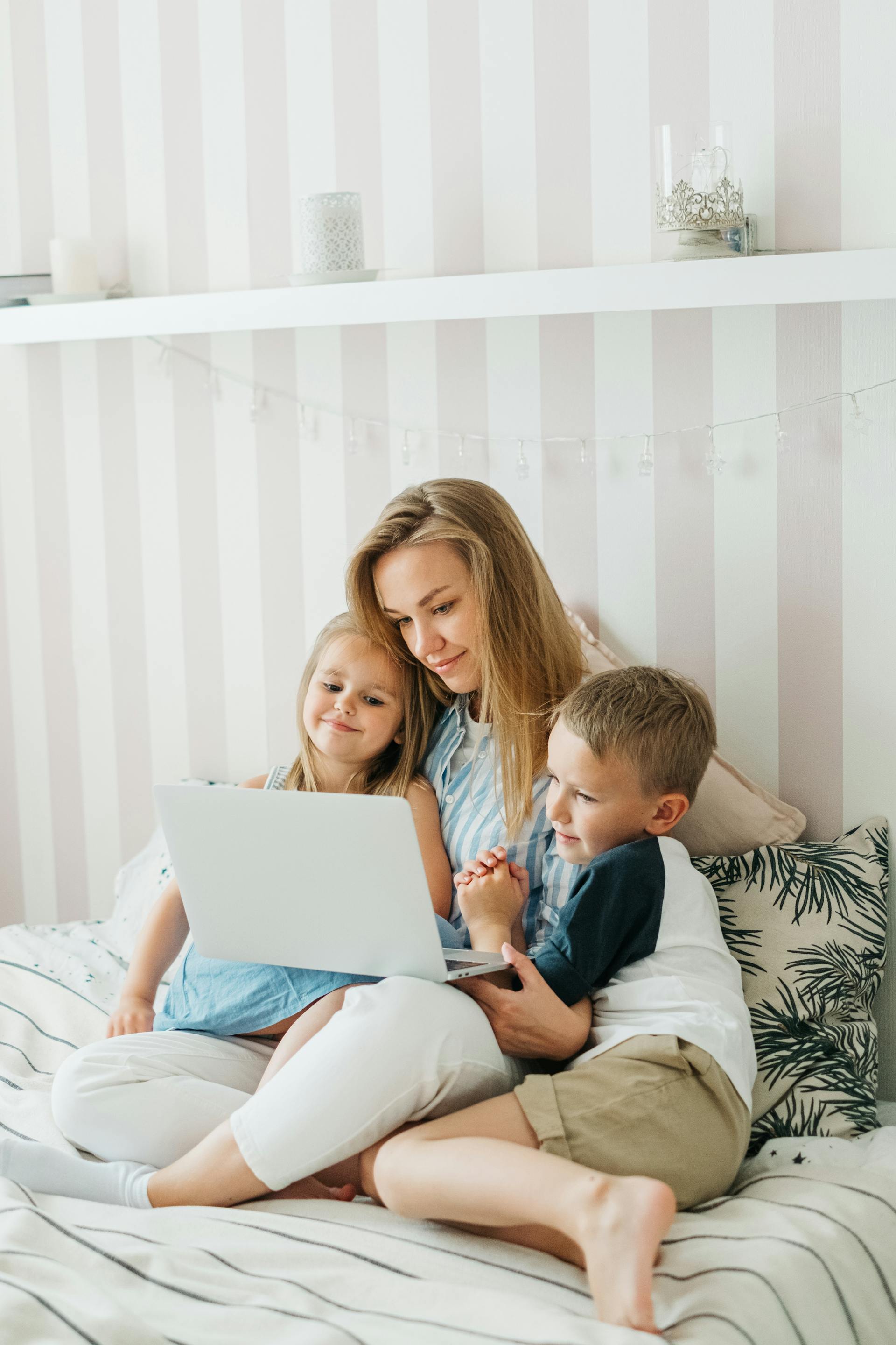 Woman using a laptop while sitting with her kids | Source: Pexels