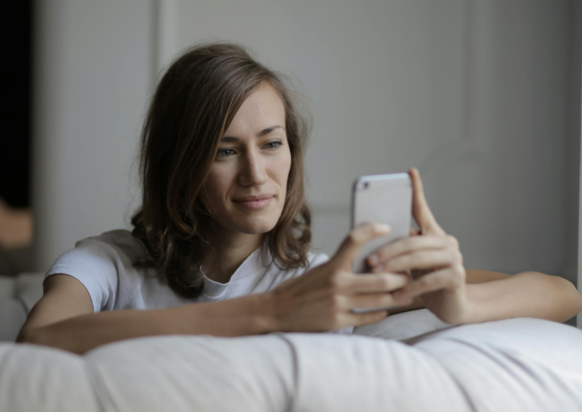 A woman smiling at her phone | Source: Pexels
