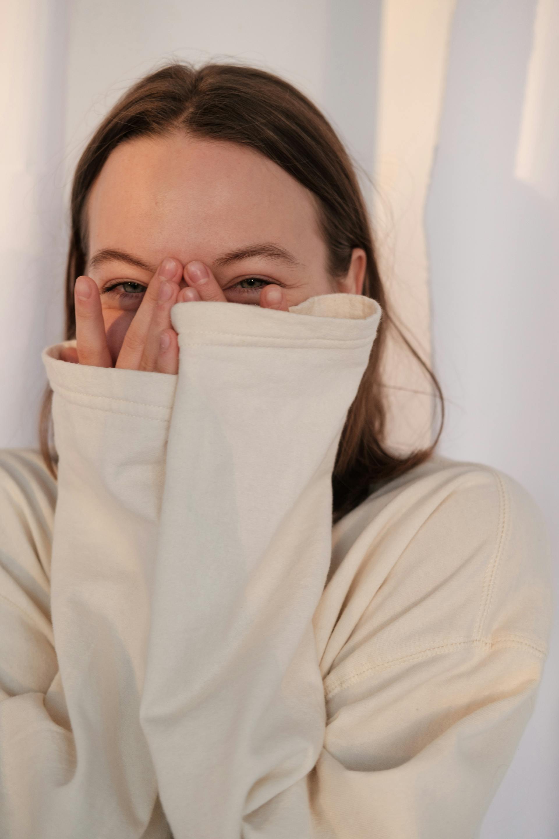 An amused woman peeking between her fingers | Source: Pexels