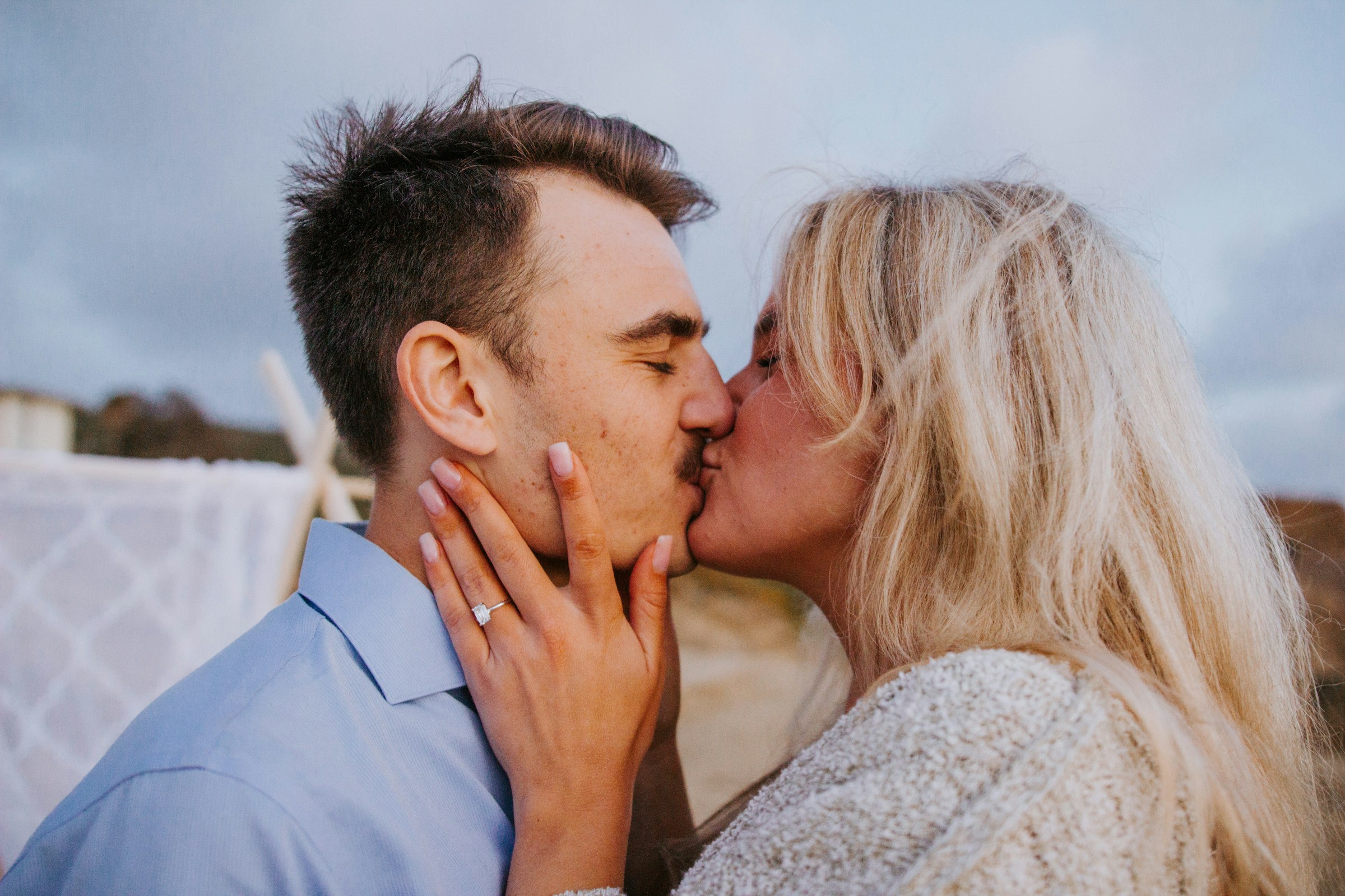 A couple kissing while showing their engagement ring | Source: Unsplash