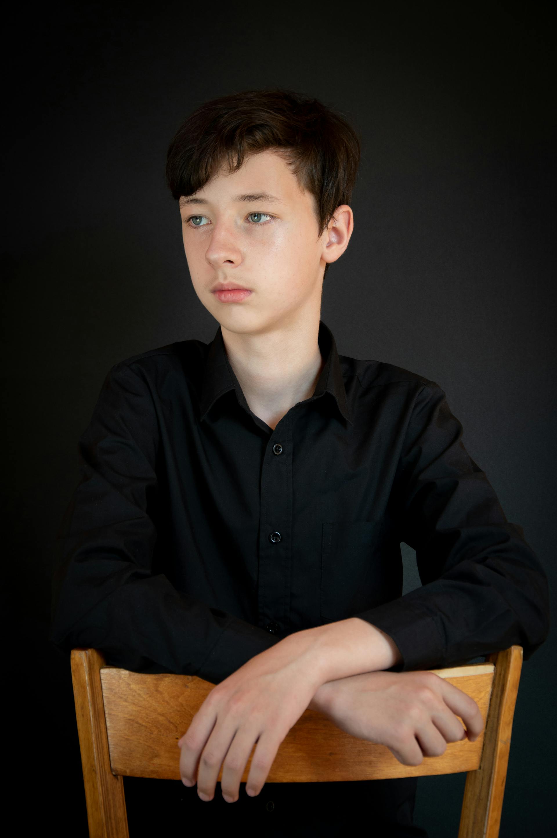 A teenage boy looking at someone with his hands resting on a chair | Source: Pexels