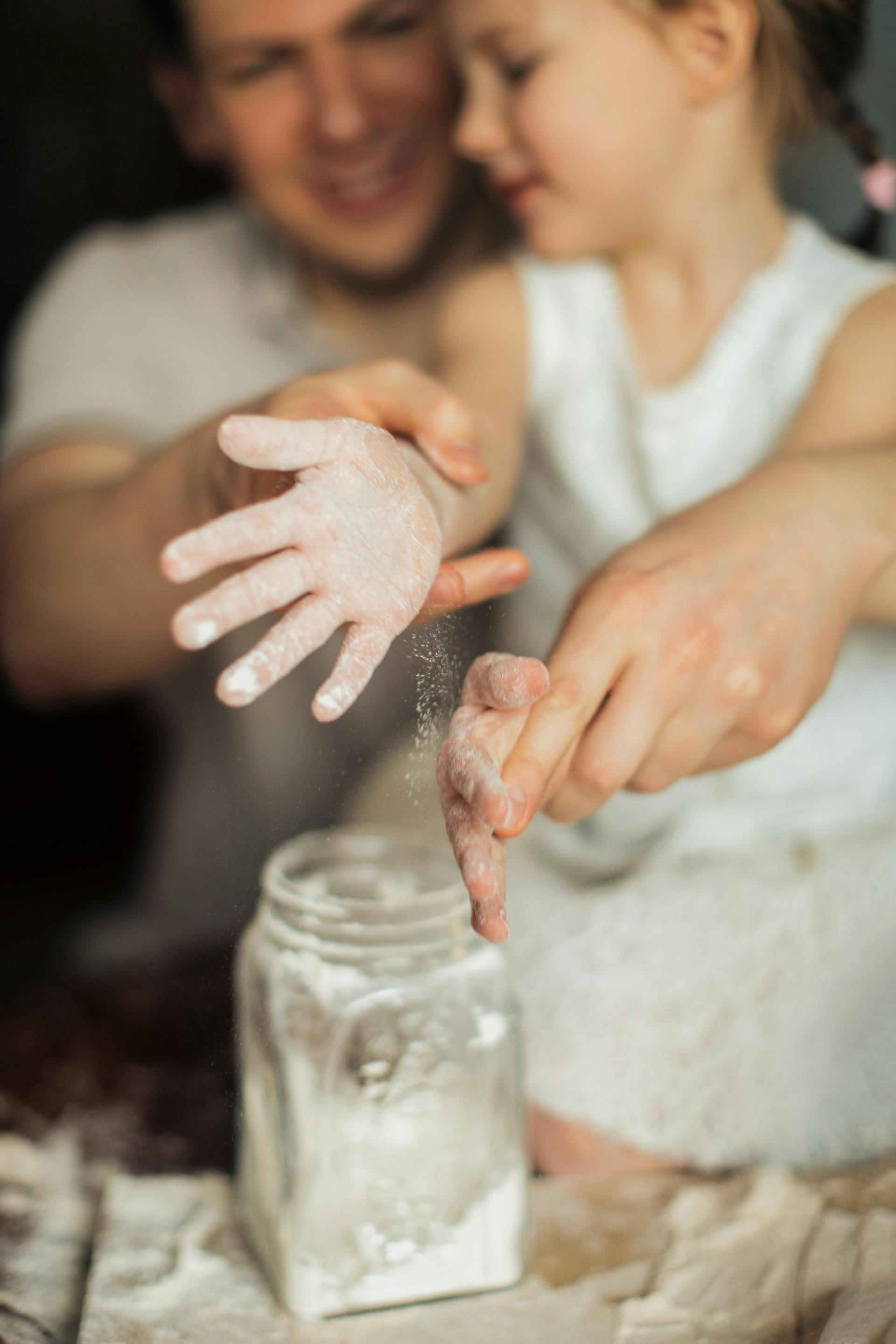 A man and a little girl making dough with flour | Source: Pexels