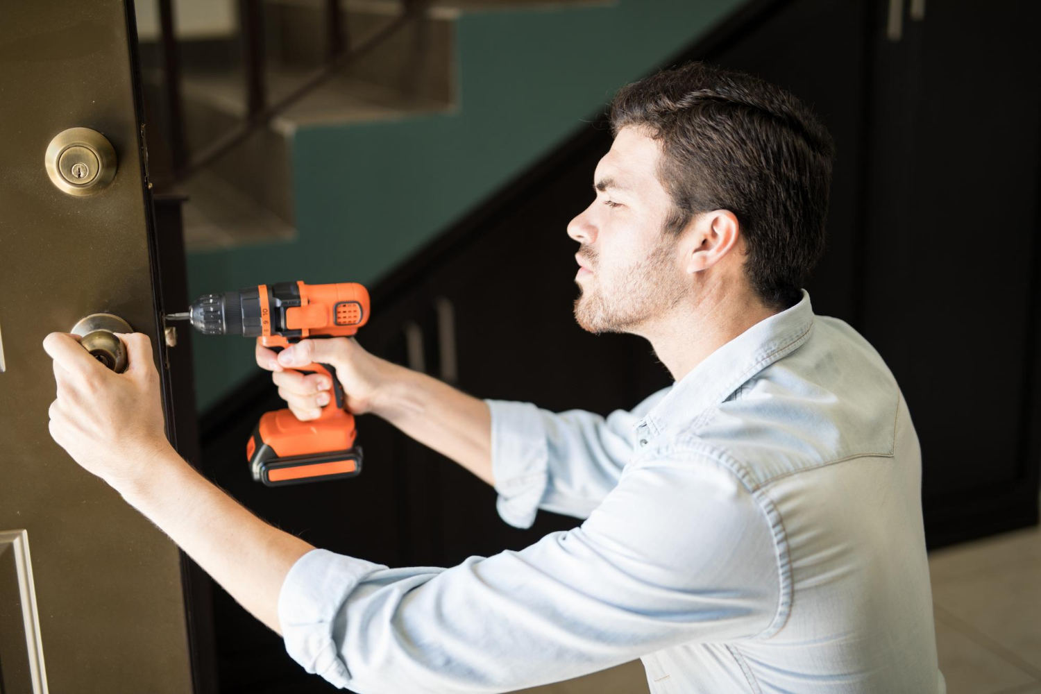 A handyman using a power drill to fix a doorknob | Source: Freepik