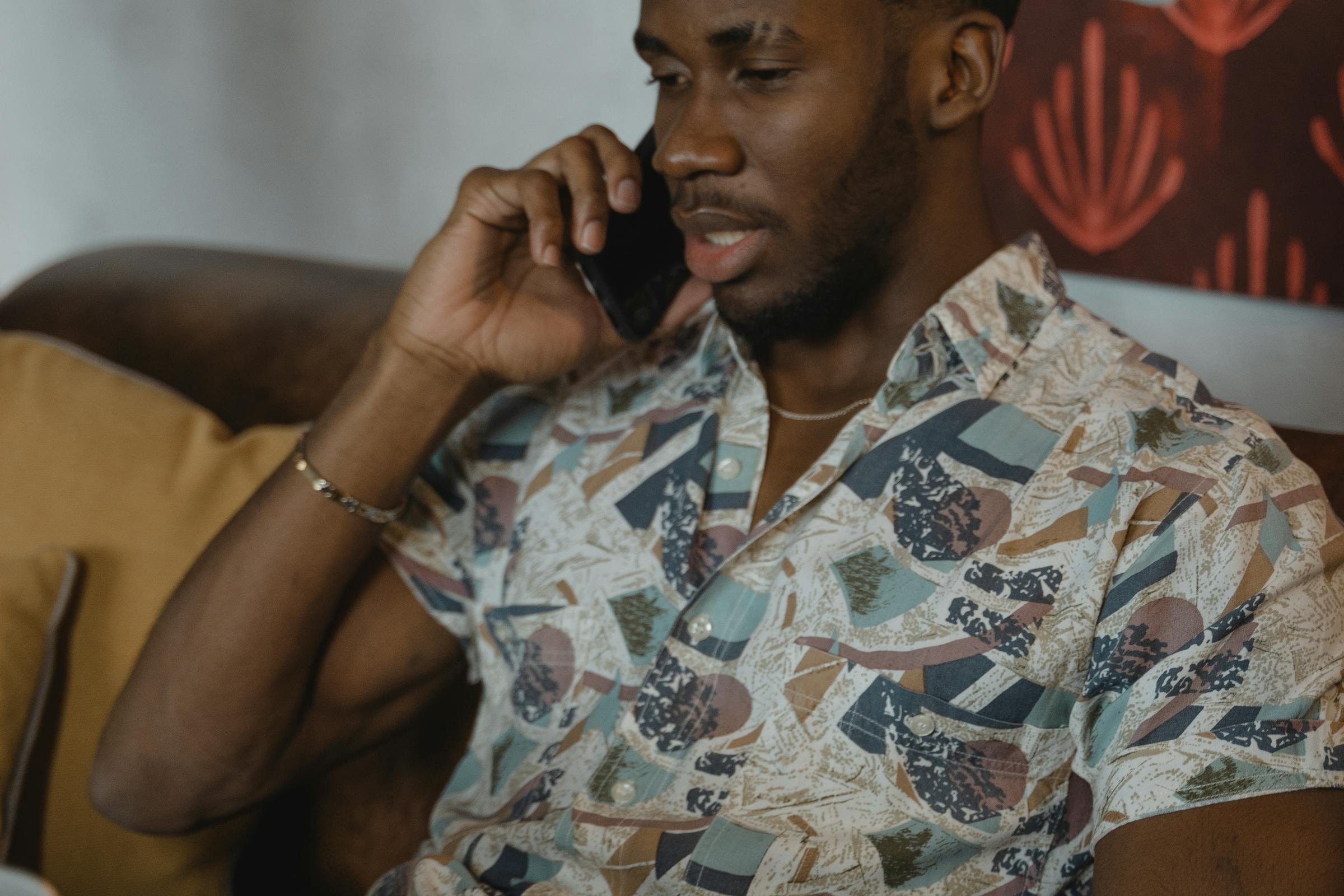 A man on a phone call from a couch looking upset | Source: Pexels