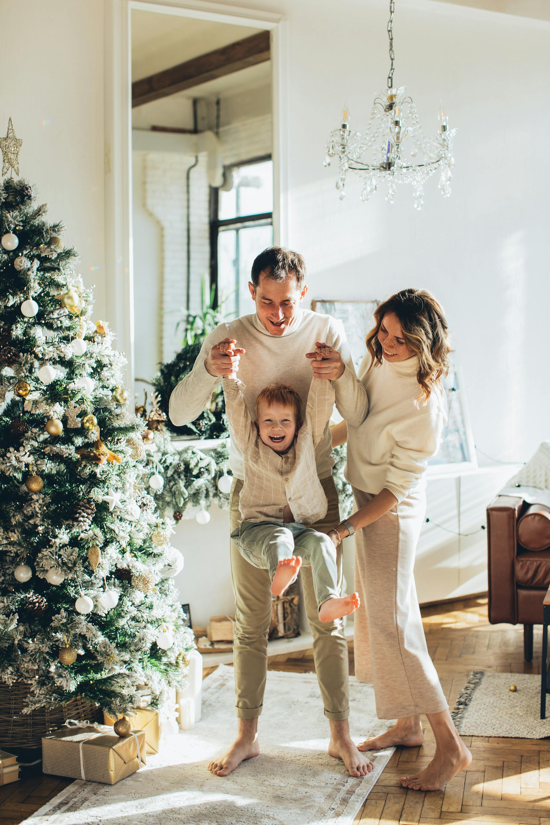 A couple playing with their young son besides a Christmas tree | Source: Pexels