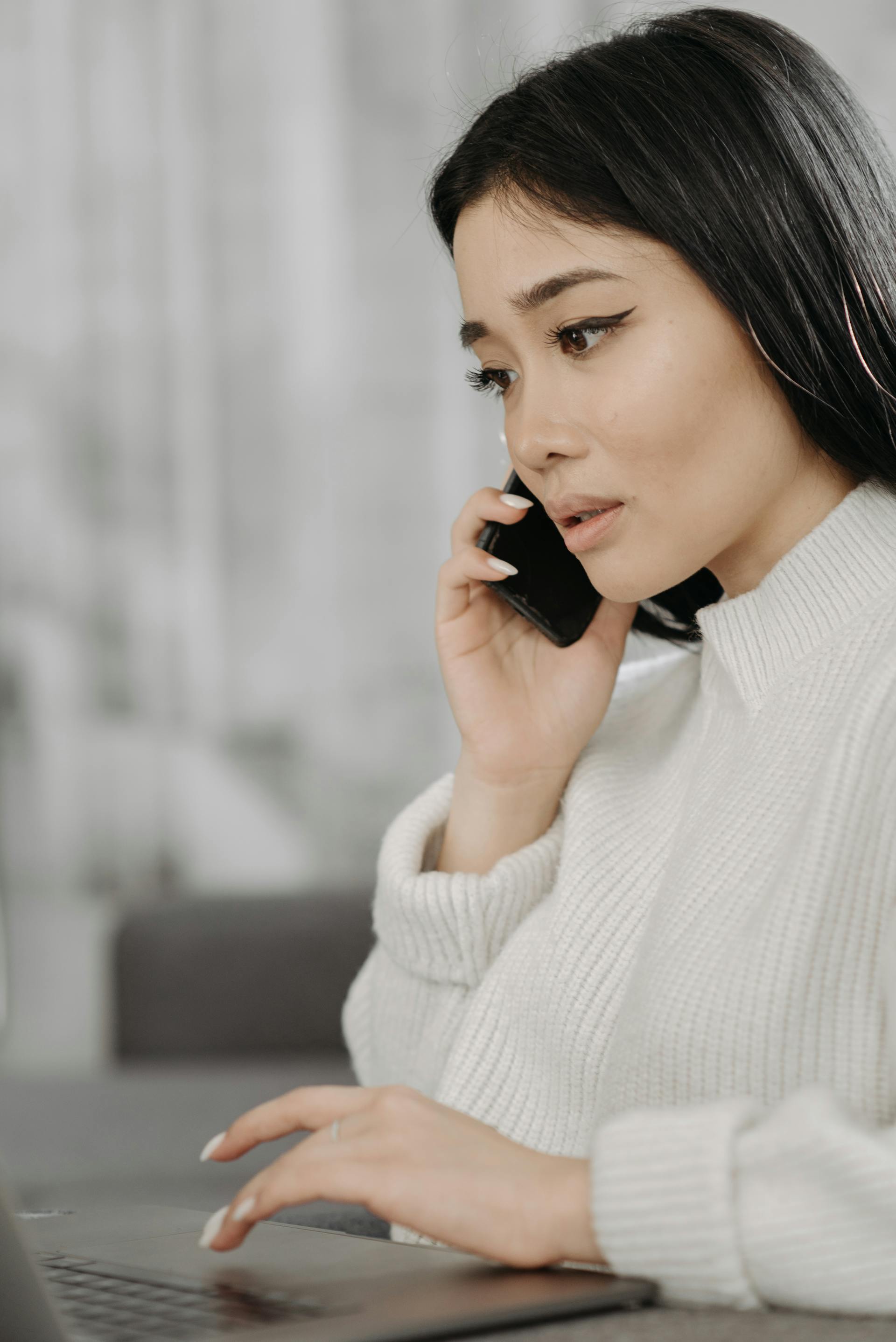 A woman with a sad expression speaking on the phone while working | Source: Pexels
