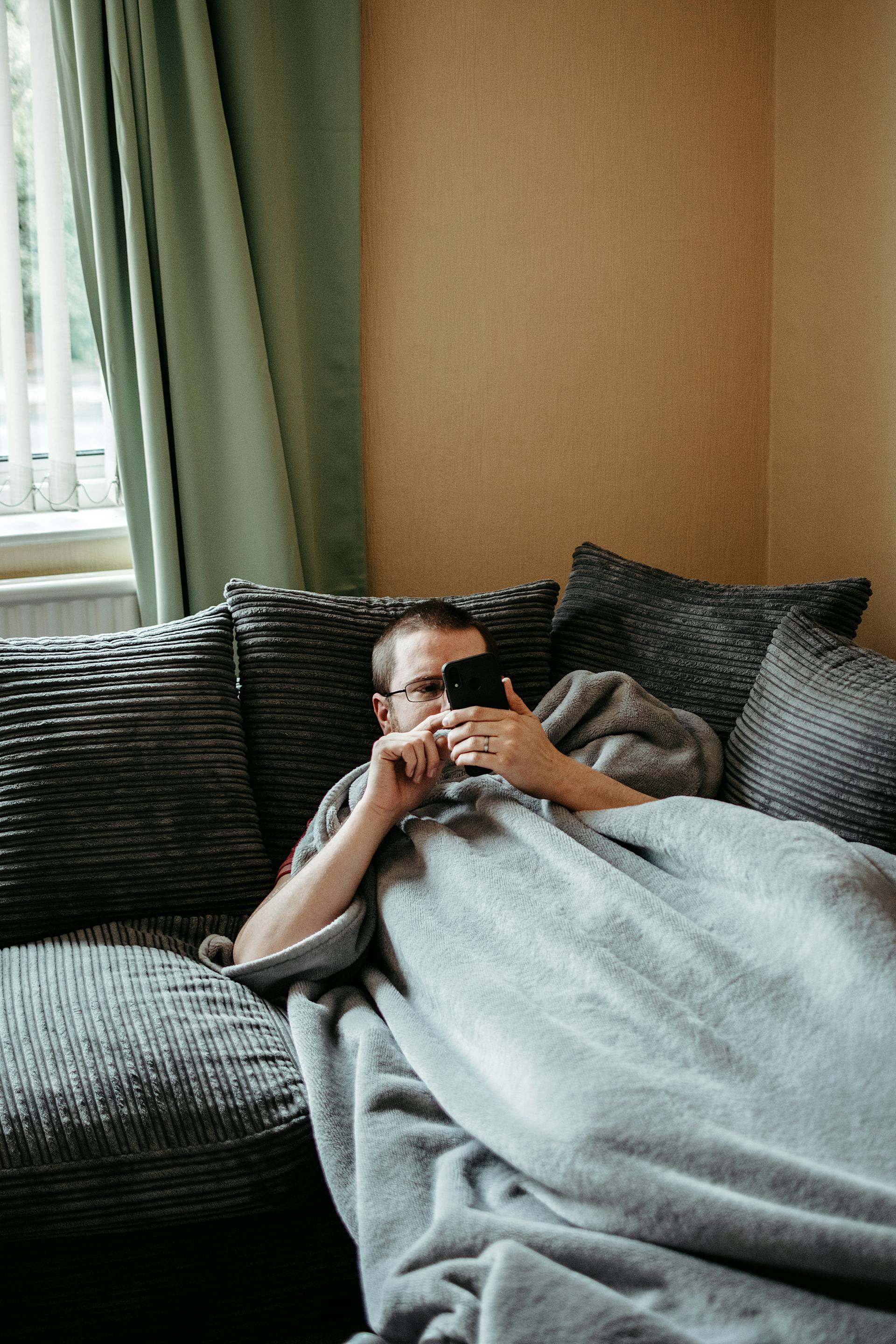 A man using his phone while lying on the couch | Source: Pexels