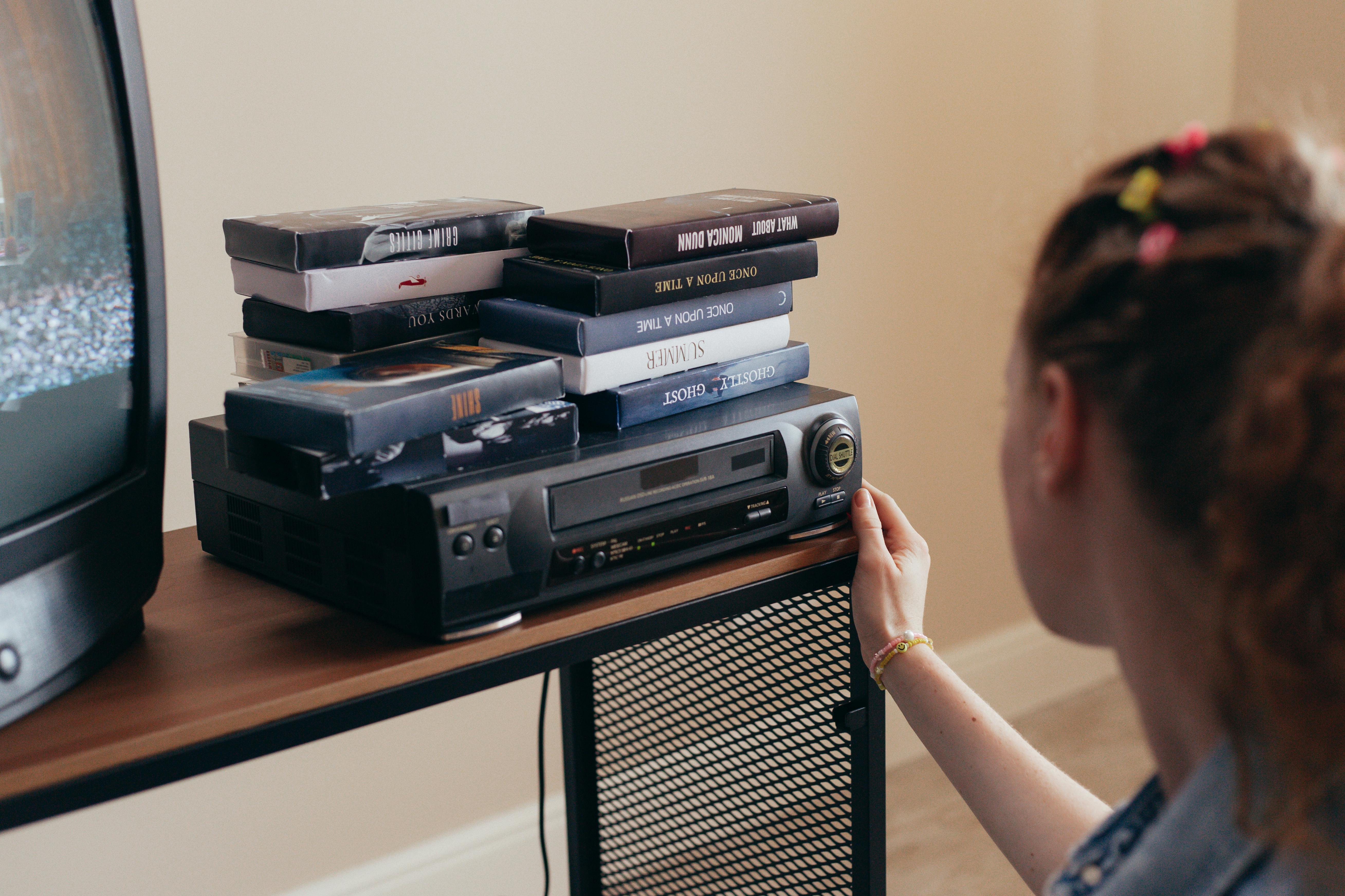 A blank television screen while a woman fiddles with a VCR player | Source: Pexels