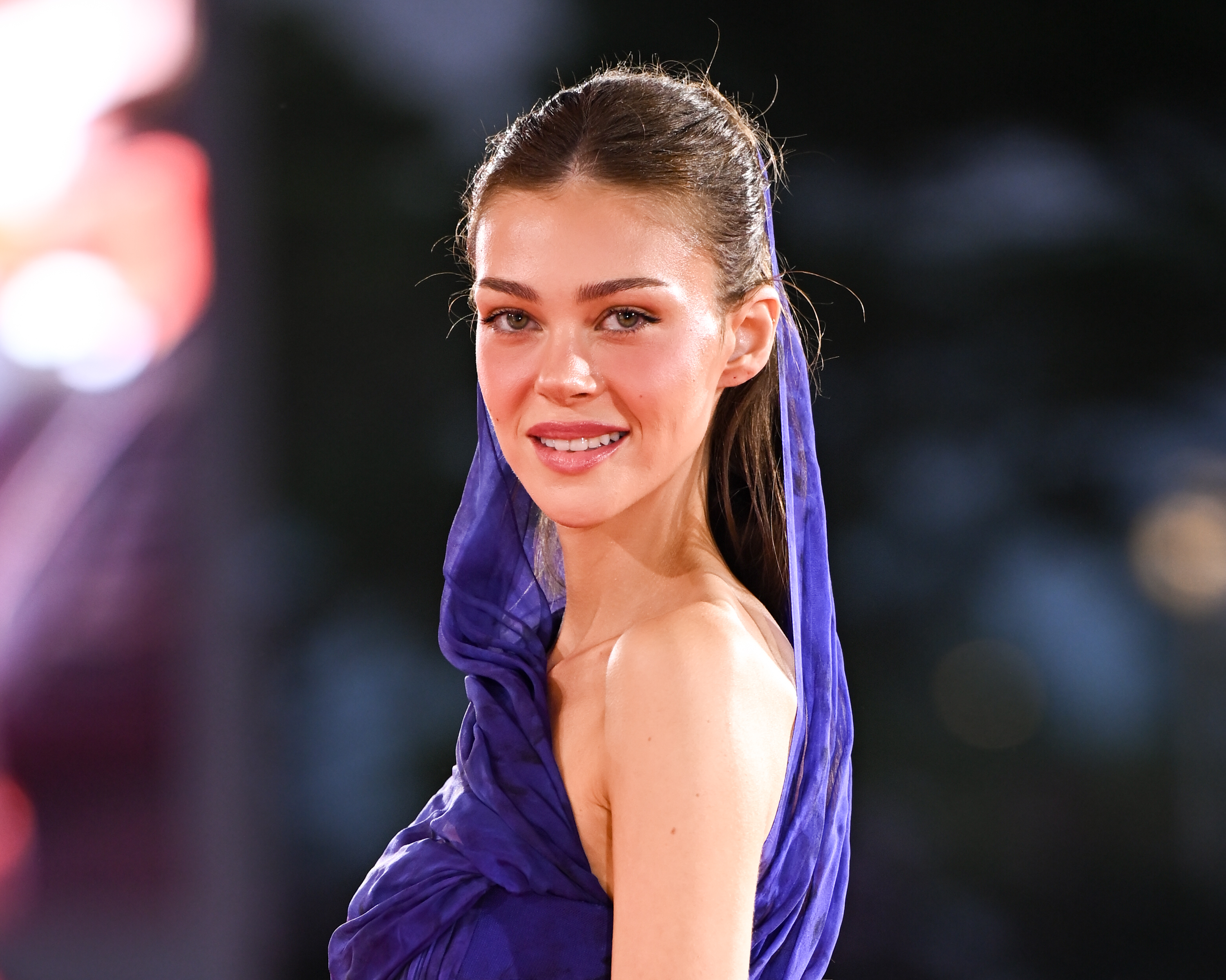 Nicola Peltz Beckham poses on the red carpet during the 83rd Venice International Film Festival in Venice, Italy, in September 2026, wearing a dramatic deep blue-purple gown with a draped detail framing her face and shoulders. | Source: Getty Images