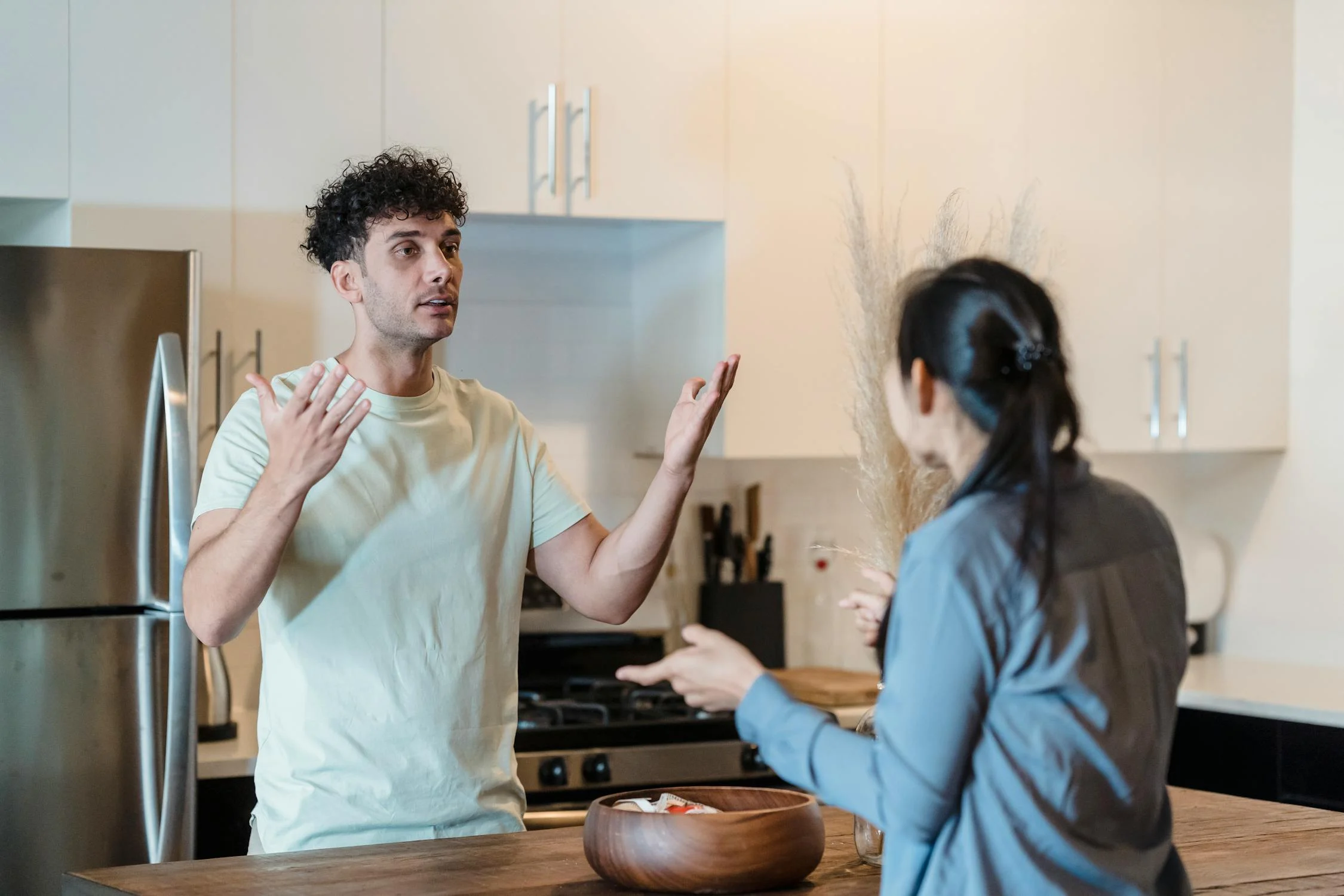 Un hombre hablando con su esposa en la cocina | Fuente: Pexels