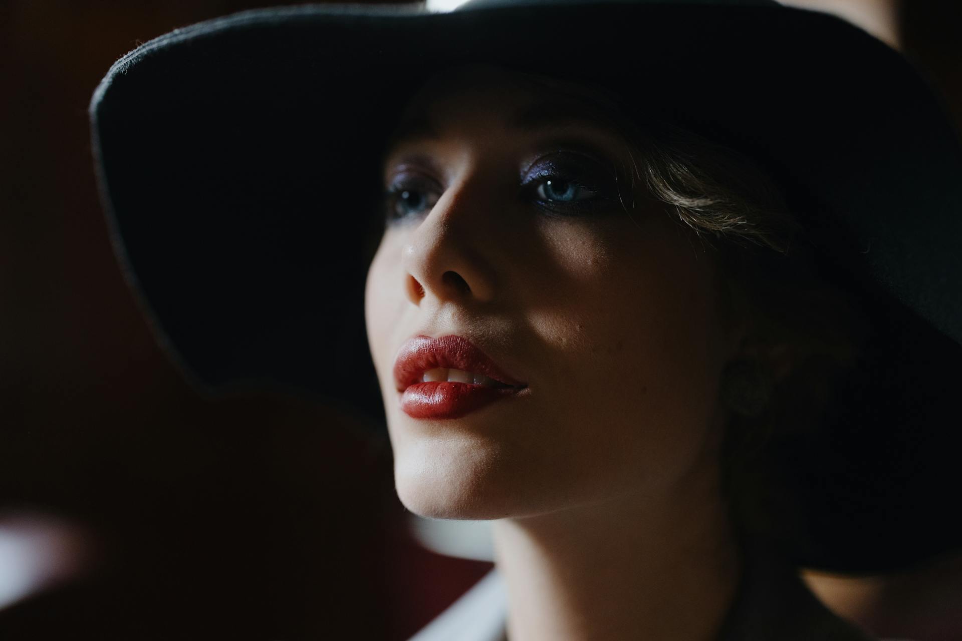 A beautiful woman with red lipstick and a black hat looking off to the side | Source: Pexels