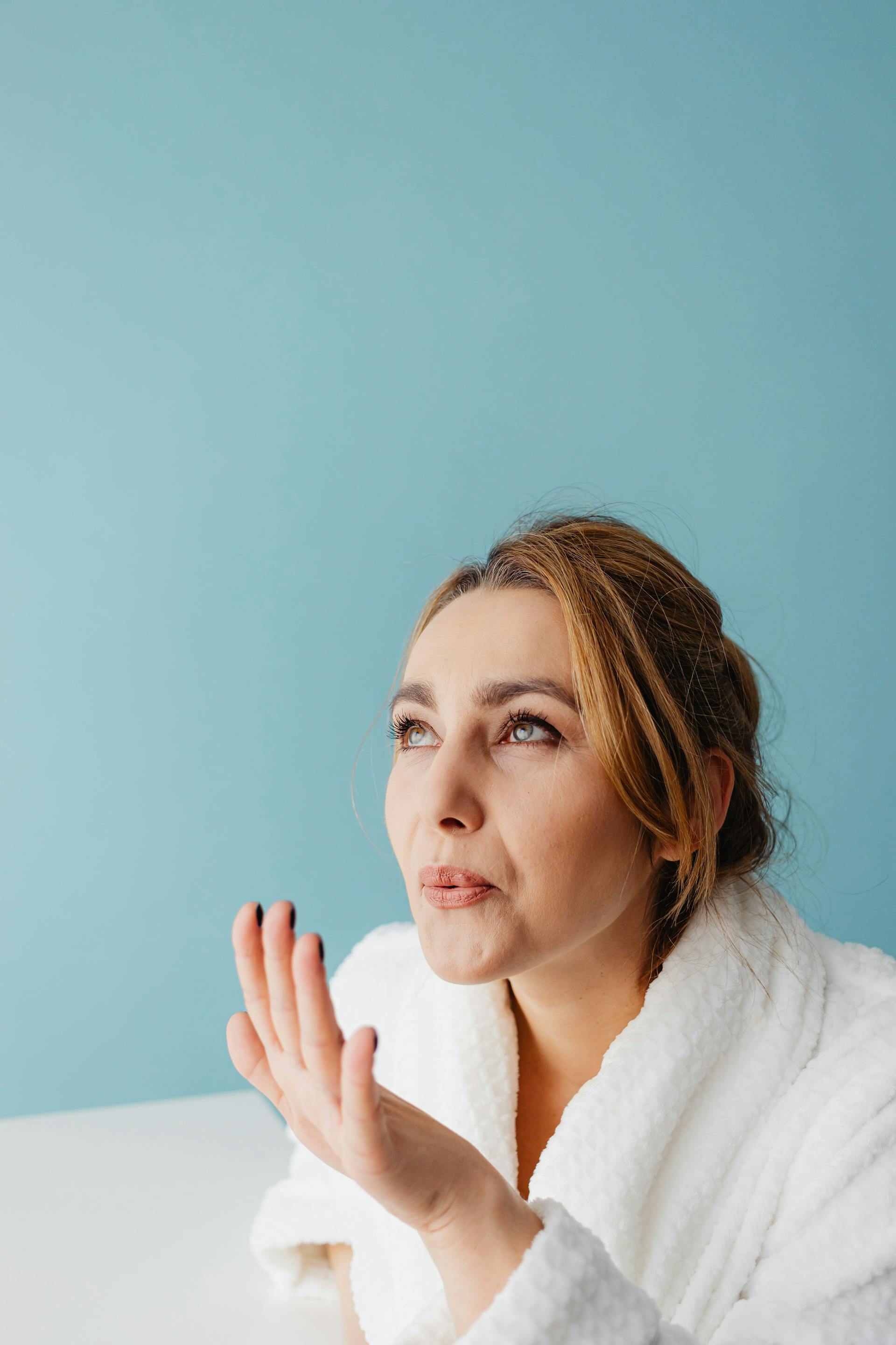 A woman in a bathrobe blowing on her nails | Source: Pexels