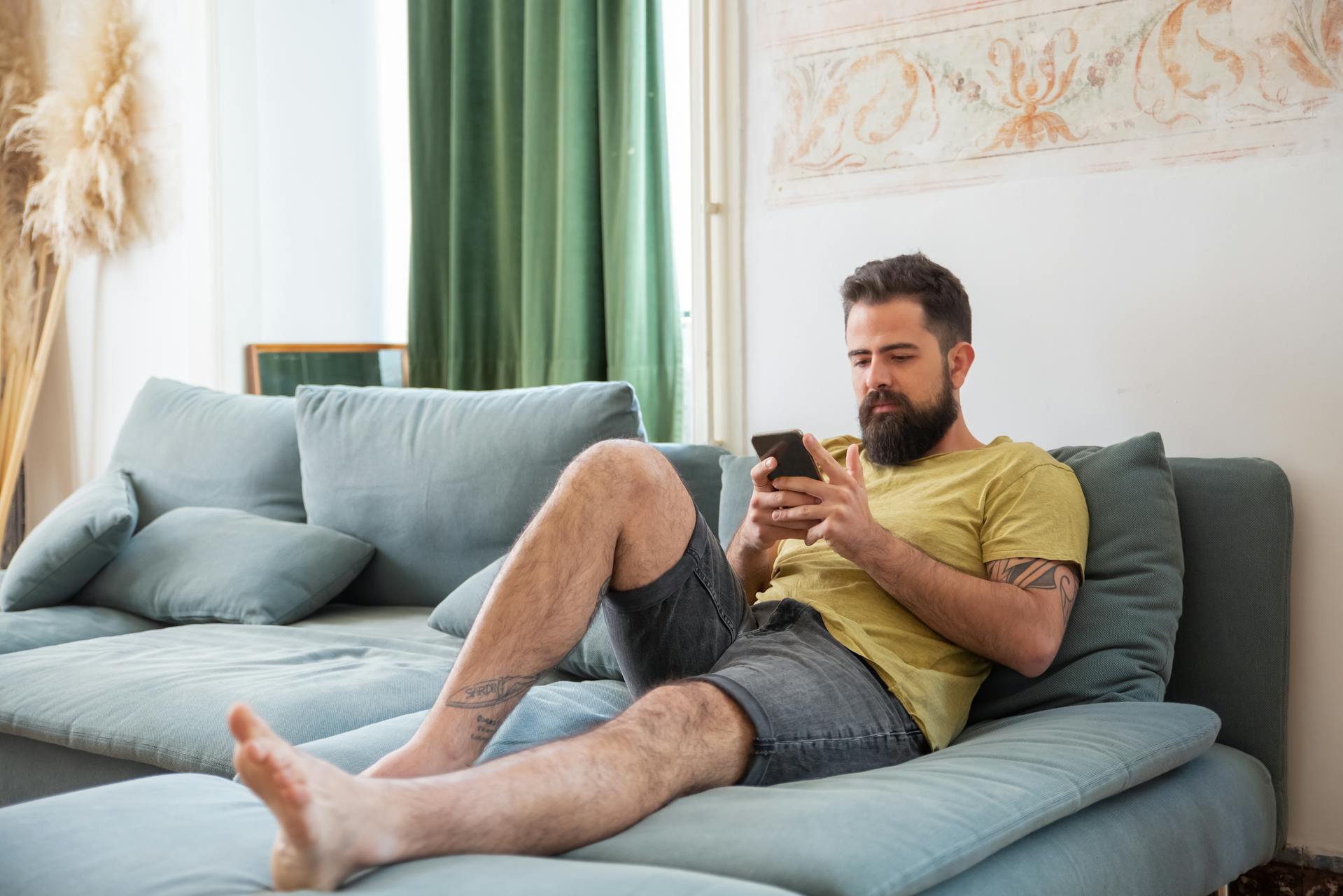 A man sitting on a couch and looking at his phone | Source: Pexels
