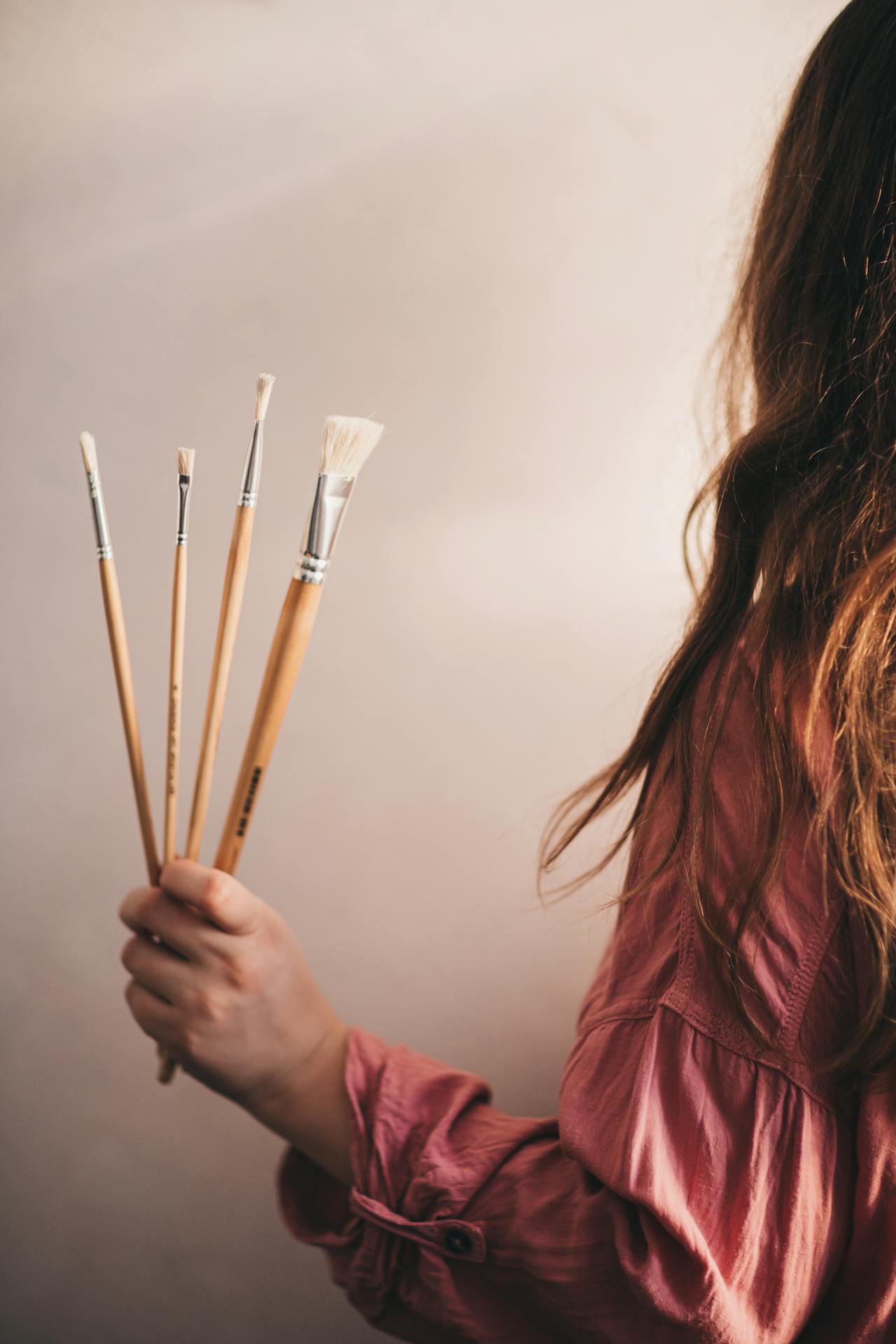 A woman holding paintbrushes | Source: Pexels