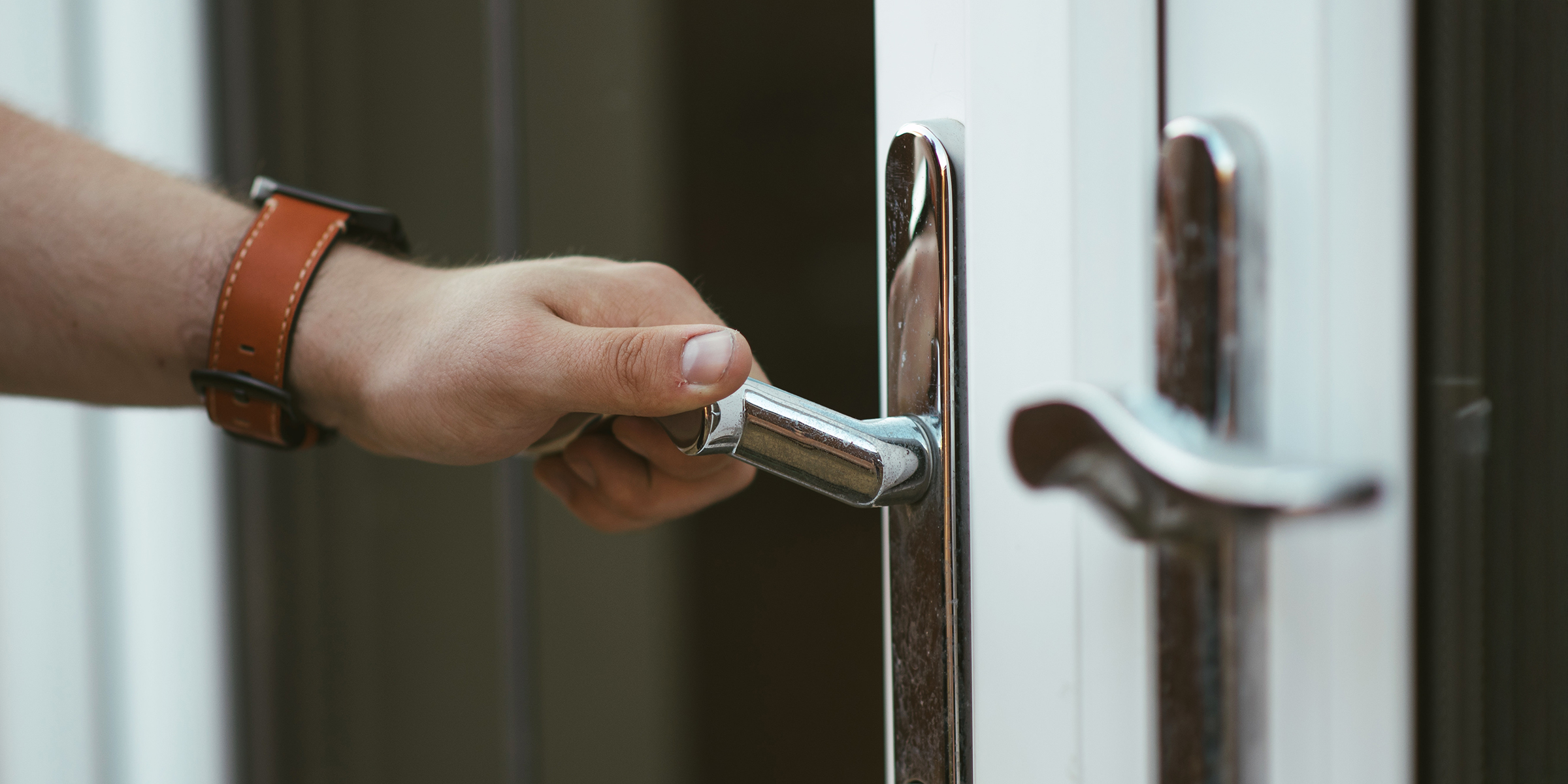 A man's hand gripping a silver door handle | Source: Shutterstock