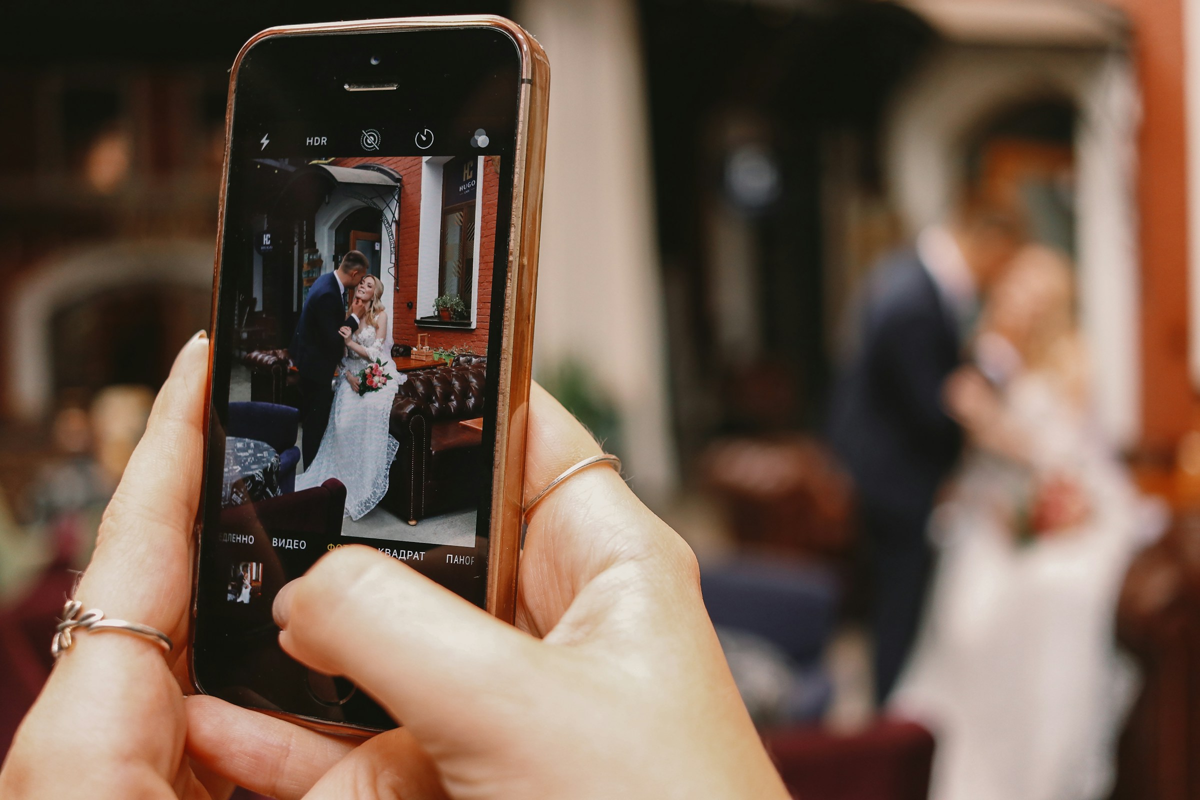 A person clicking a photo of a bride and groom on their phone | Source: Unsplash
