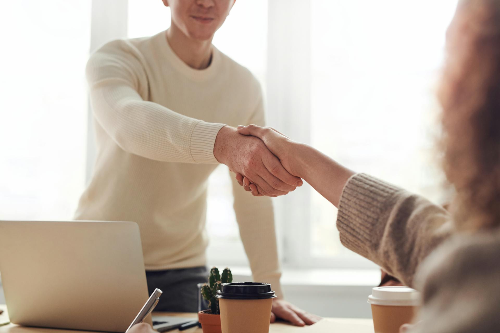 A woman shaking hands with a man in an office | Source: Pexels