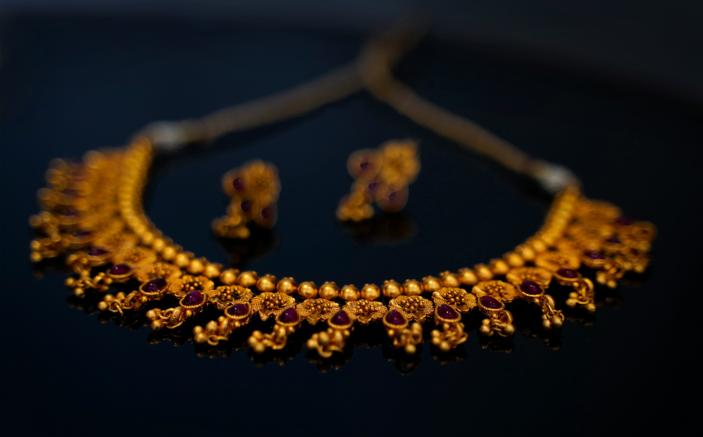 A golden necklace and matching earrings with red stones | Source: Unsplash
