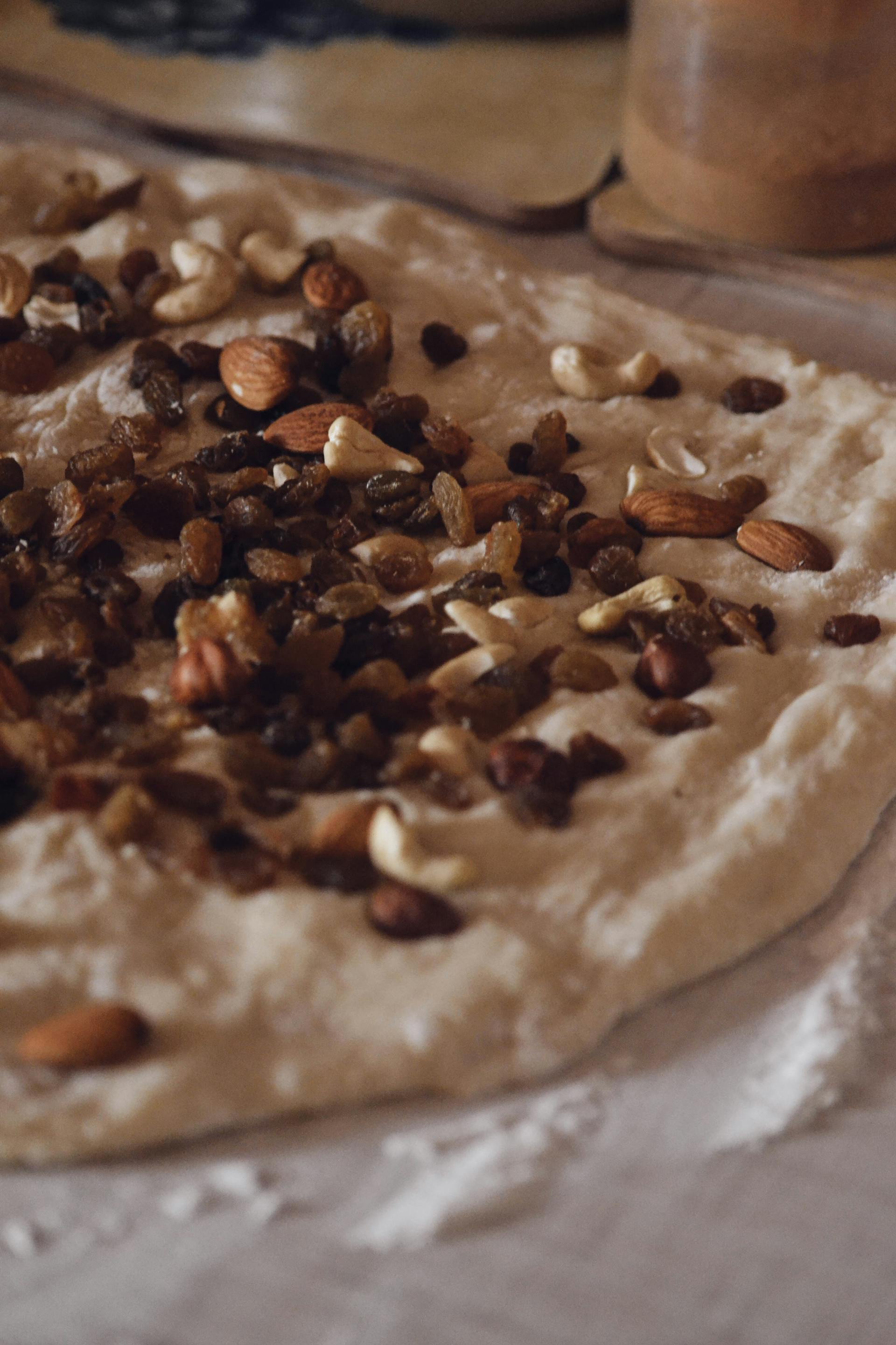 Close-up shot of dough garnished with nuts and raisins | Source: Pexels