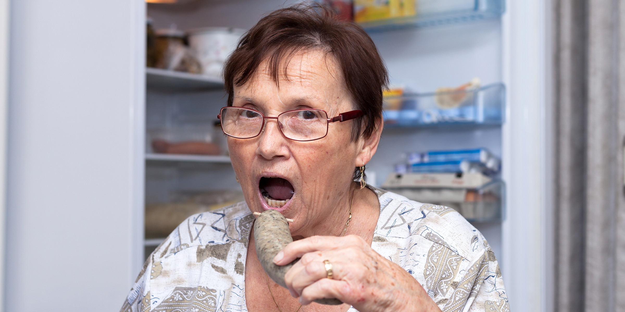 A woman eating in front of the fridge | Source: Shutterstock