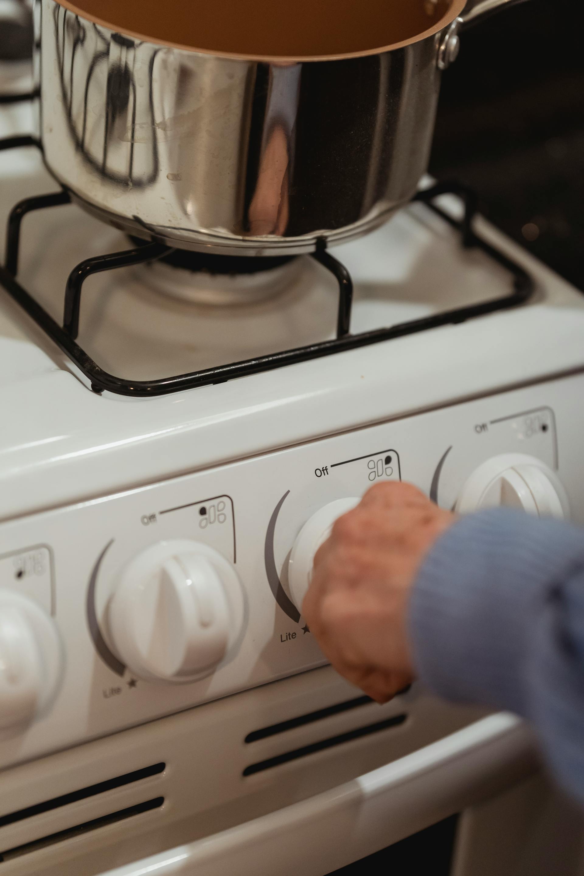 Close-up of a woman turning a stove knob | Source: Pexels