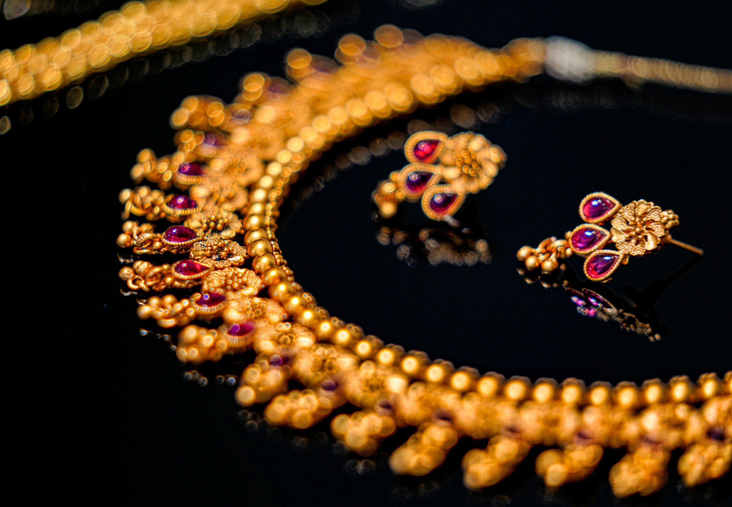 A golden necklace with earrings decorated with red and purple gemstones | Source: Unsplash