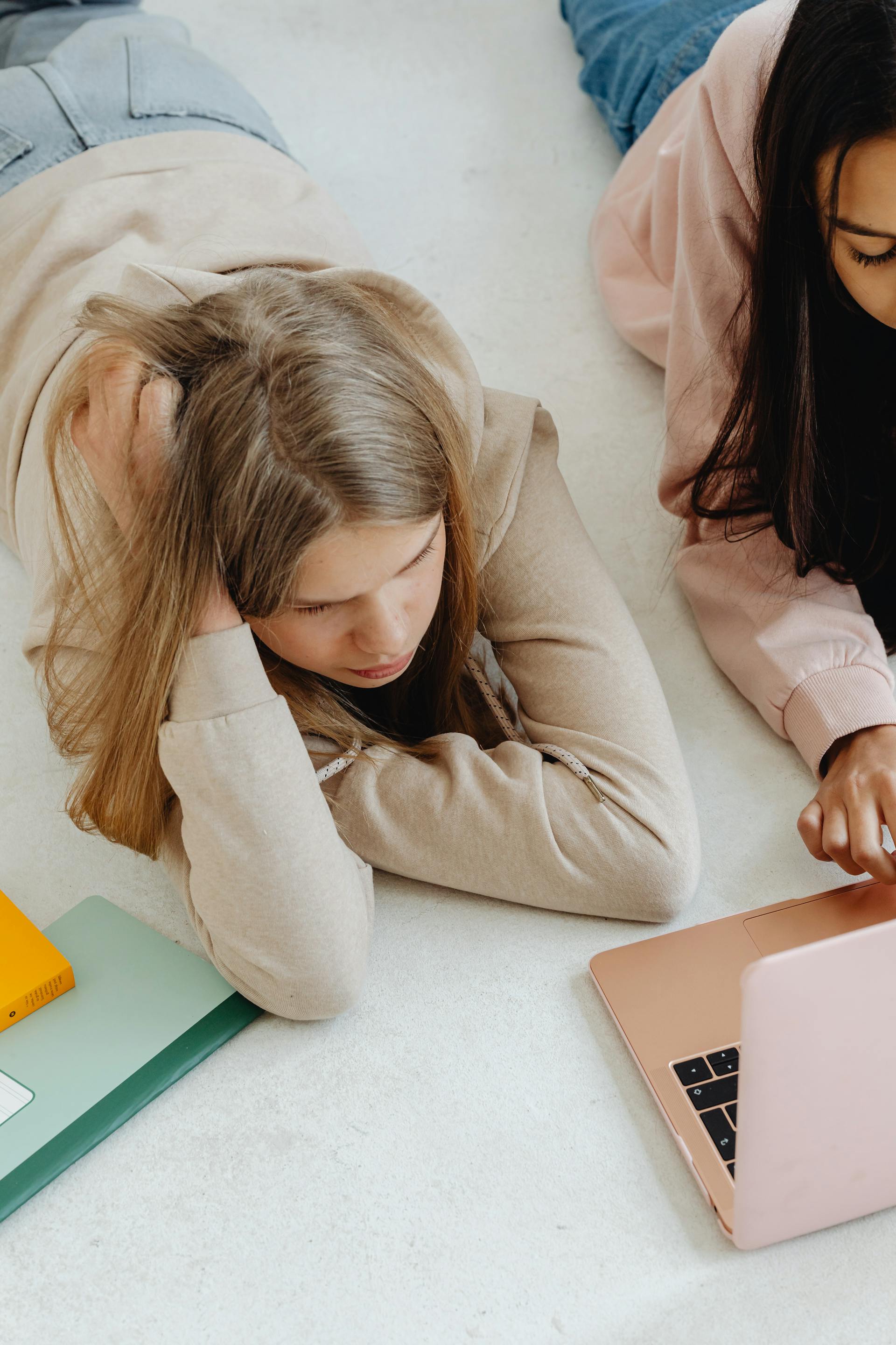 Two teen girls lying on the floor together | Source: Pexels