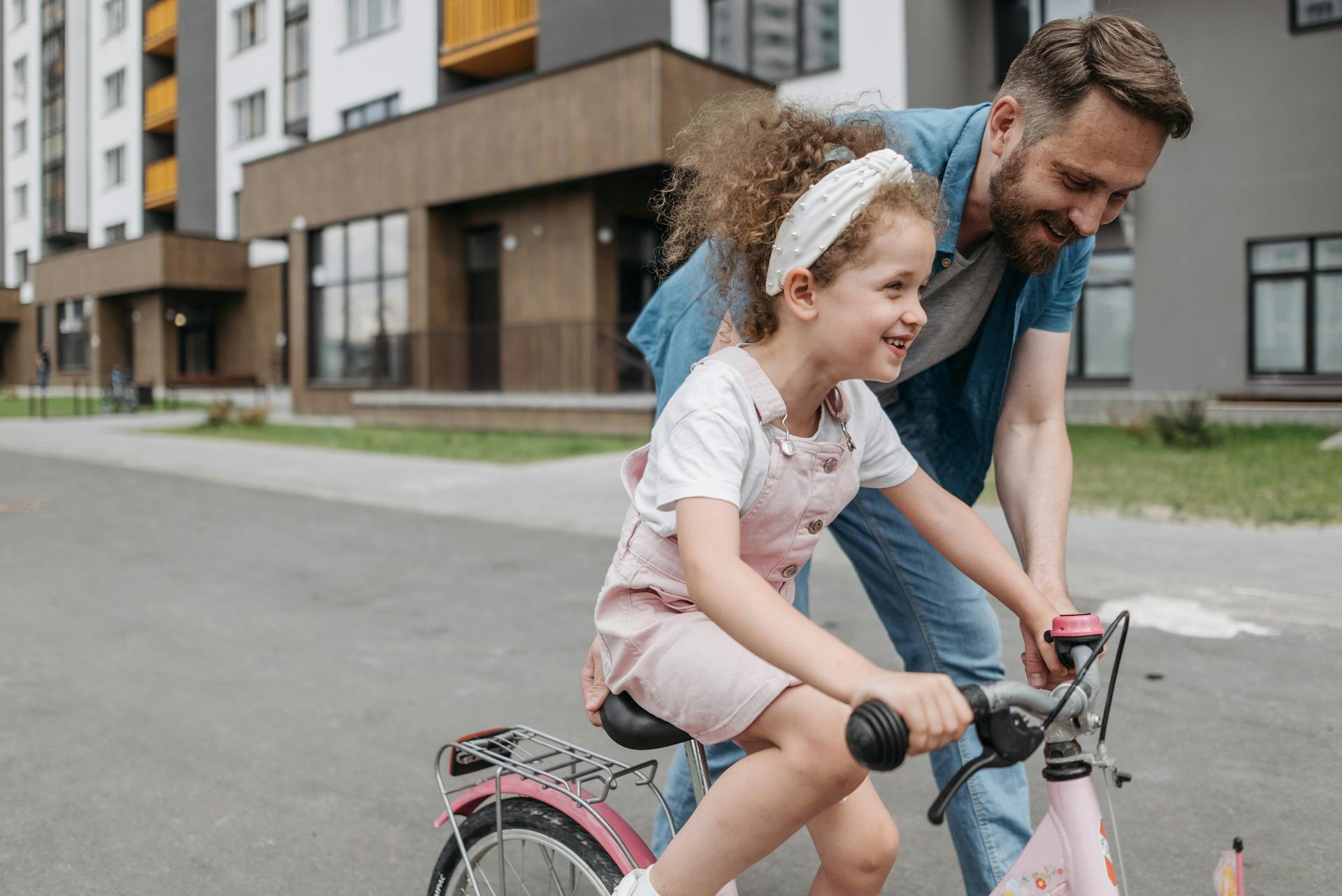 A father teaching his little daughter to ride a bike | Source: Pexels