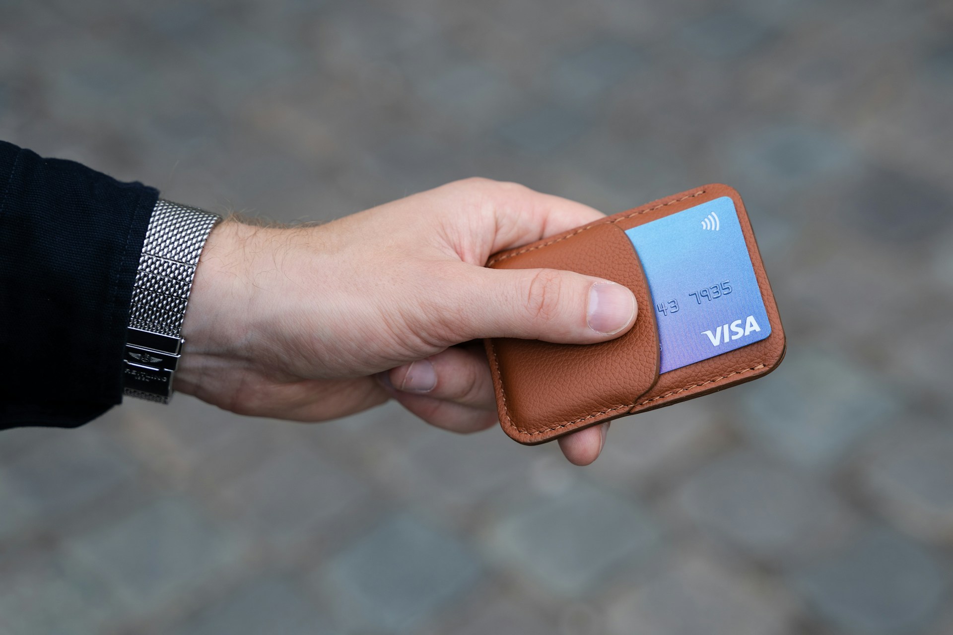 A man holding a bank card in a leather card holder | Source: Unsplash