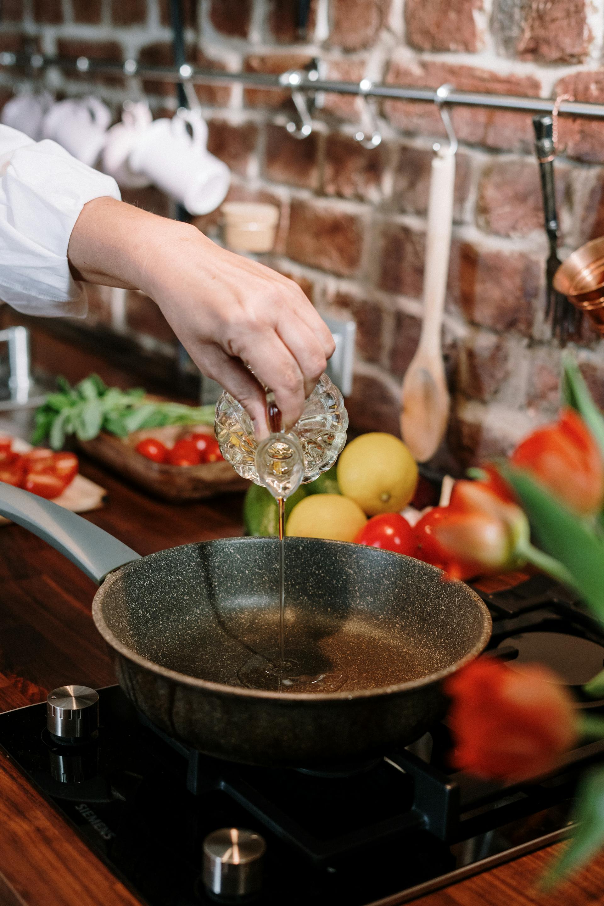 A woman pouring oil in a pan | Source: Pexels