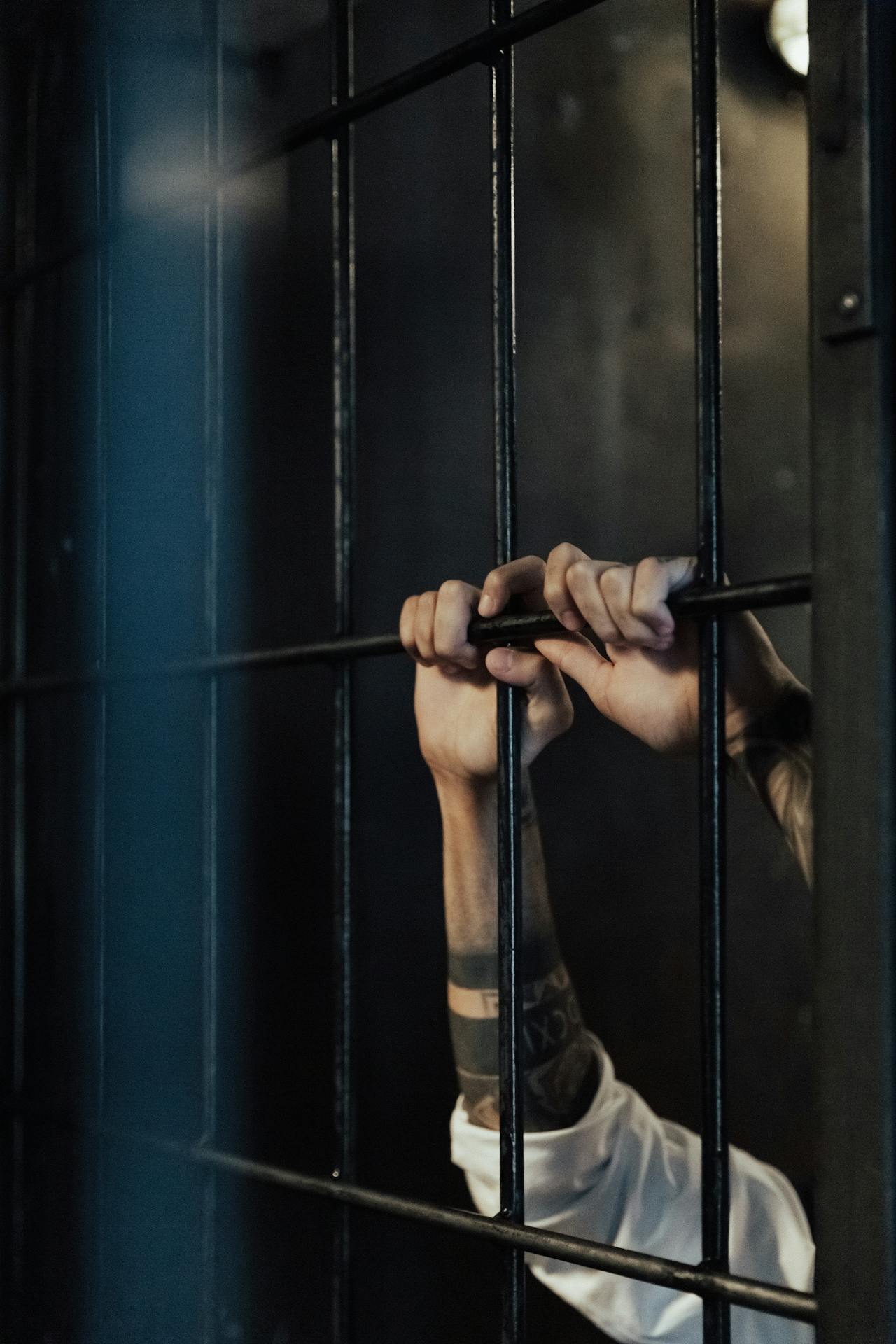 A prisoner holding metal railings in a jail | Source: Pexels