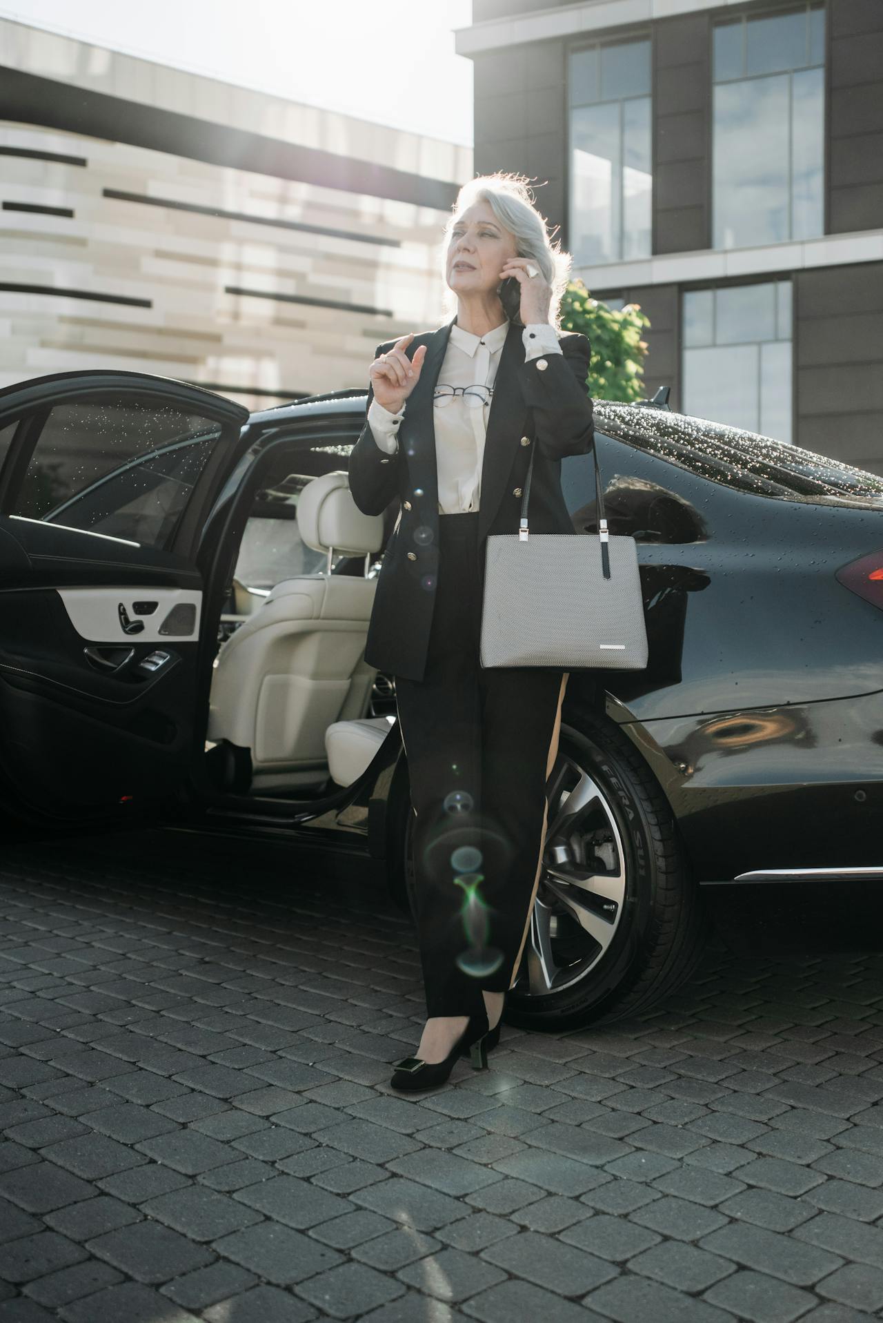 An elegant eldery woman standing beside her car and talking on the phone | Source: Pexels