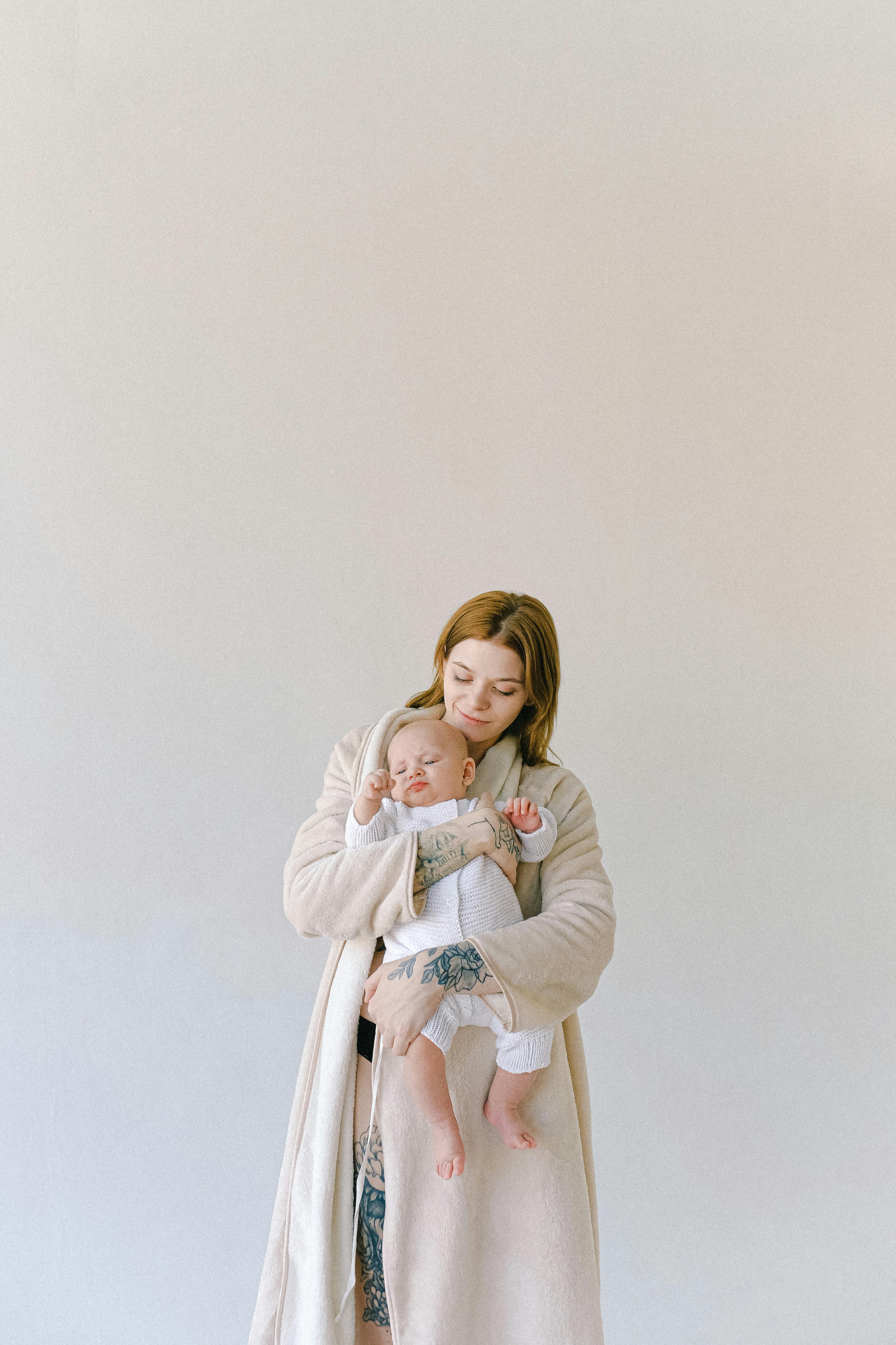 A woman standing holding a baby | Source: Pexels