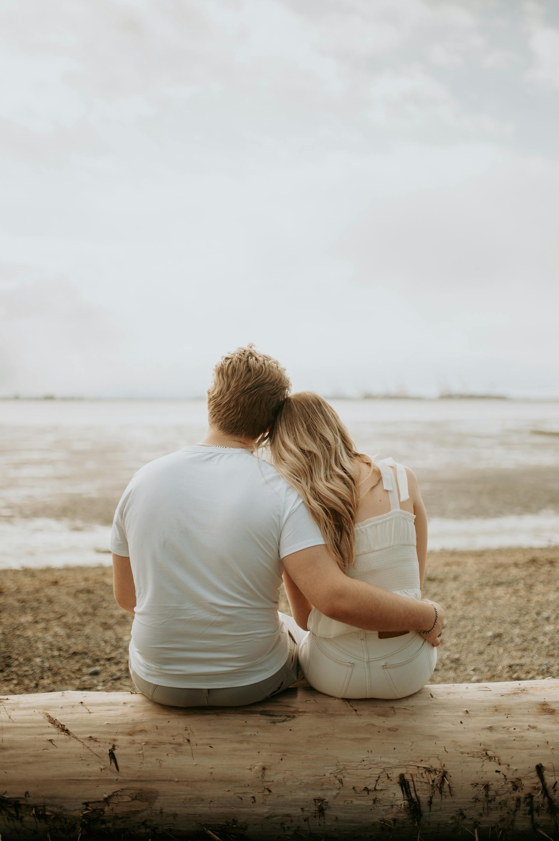 A back-view of a couple sitting on a beach | Source: Pexels