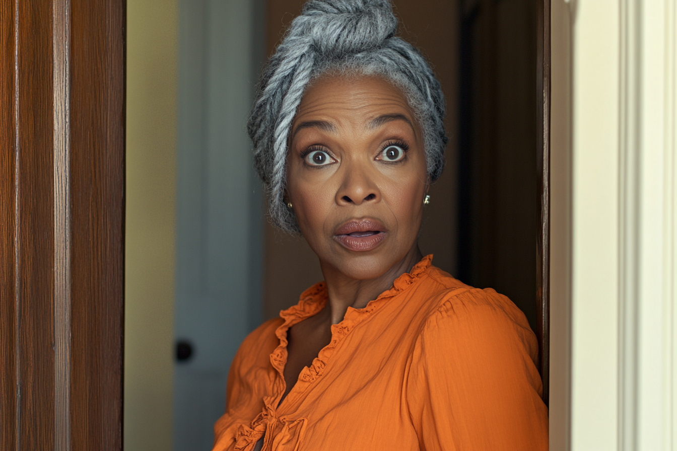 A woman standing by the doorway of an apartment looking shocked | Source: Midjourney