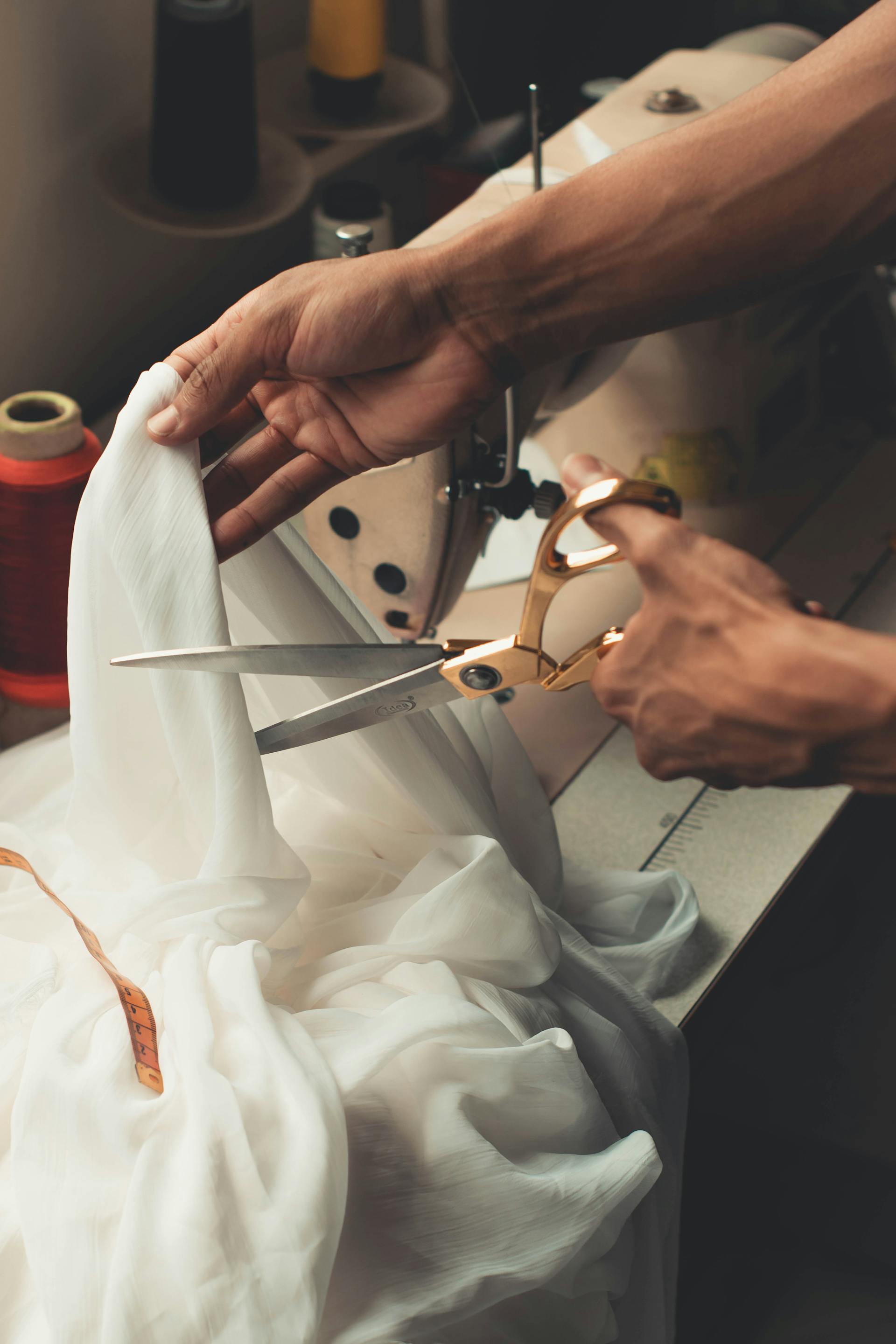 Someone using scissors to cut white fabric | Source: Pexels