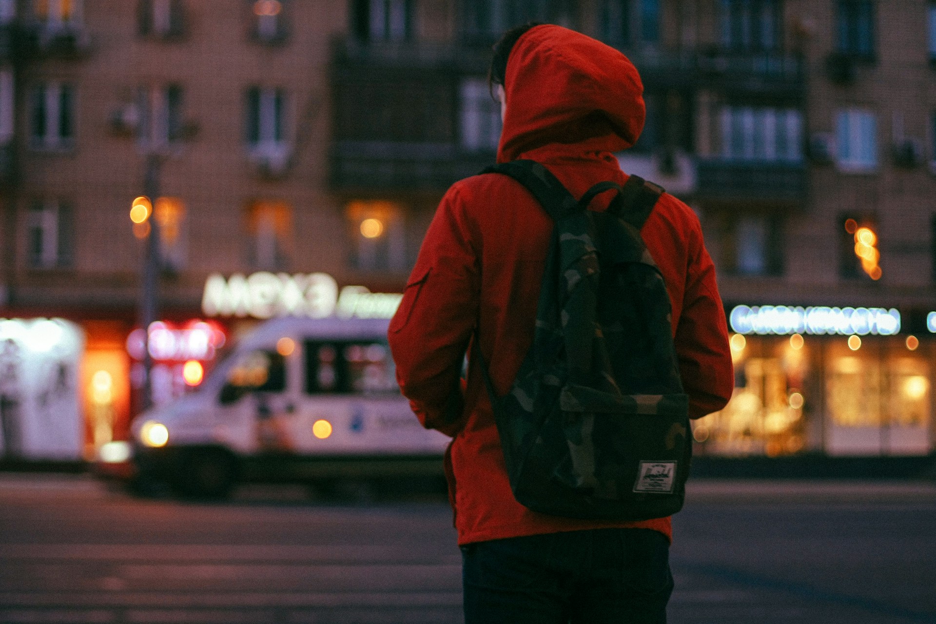 A lonely man in a red hoodie standing on the street at dusk | Source: Unsplash