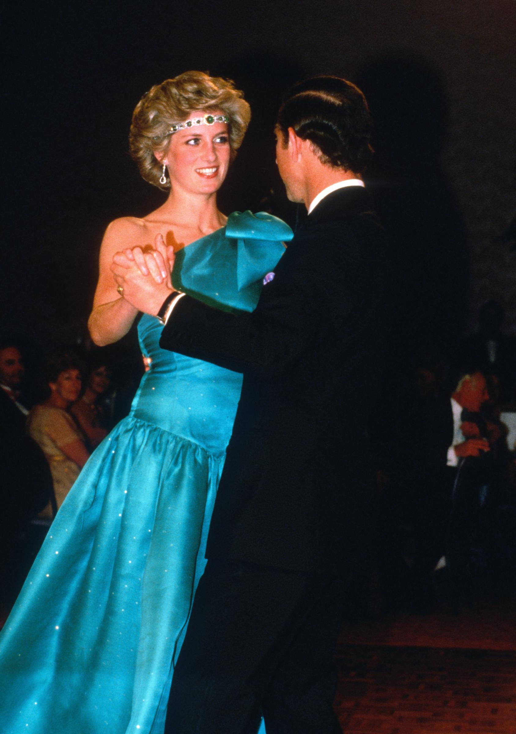 Prince Charles, Prince of Wales and Diana, Princess of Wales, wearing a green satin evening dress designed by David and Elizabeth Emanuel and an emerald necklace as a headband, dance together during a gala dinner dance at the Southern Cross Hotel on October 31, 1985 in Melbourne, Australia. | Source: Getty Images