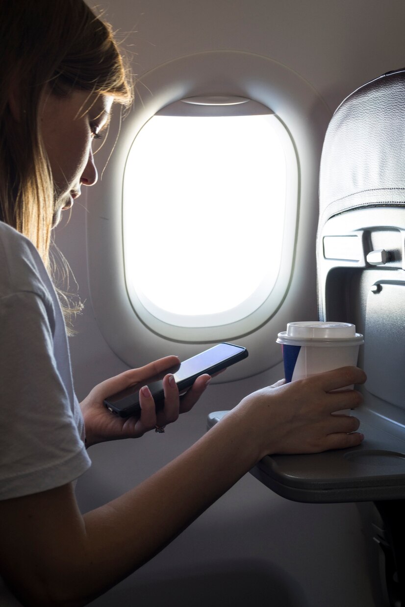 Uma mulher olhando para o seu telefone em um avião | Fonte: Pexels