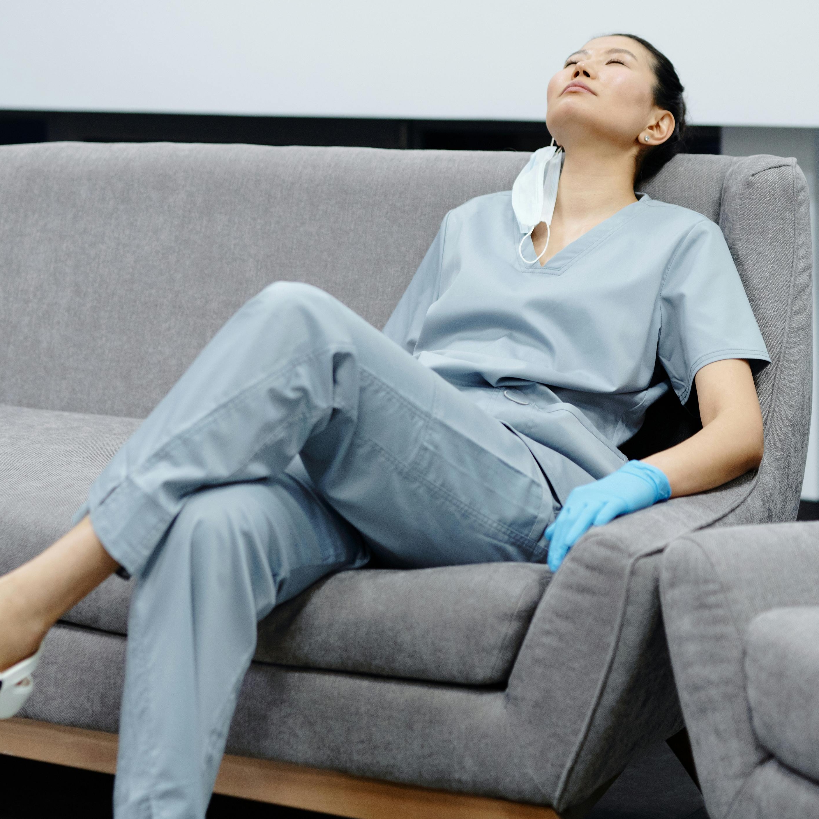 A woman in a nurse uniform crashed out on a couch | Source: Pexels