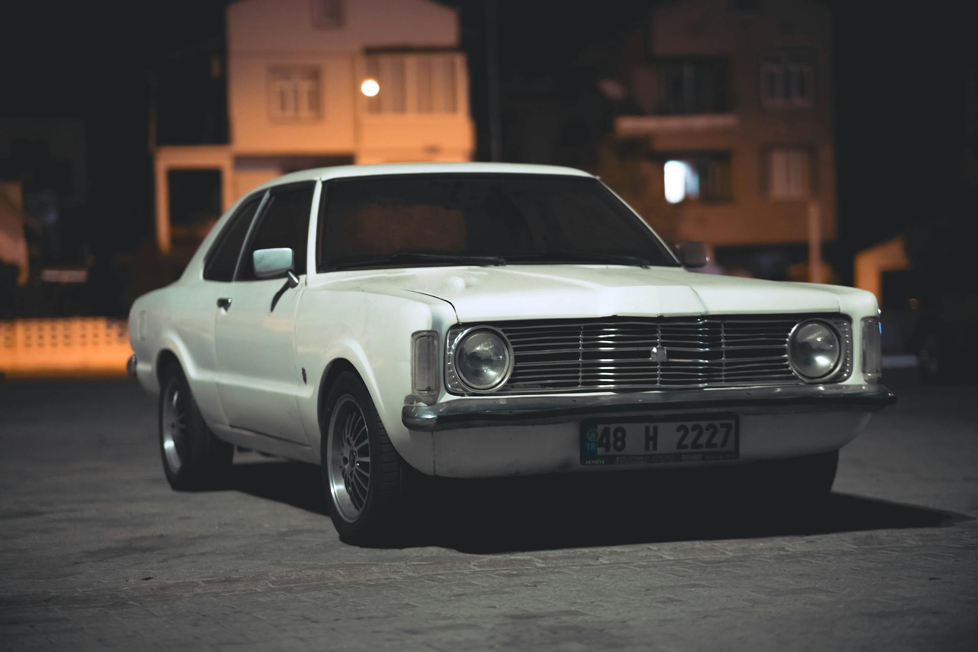A vintage white car parked on a street at night | Source: Pexels